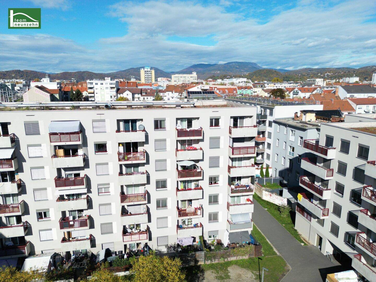 Wohngebäude mit zahlreichen Balkonen und weitem Blick über die Stadt bis zu den Bergen.