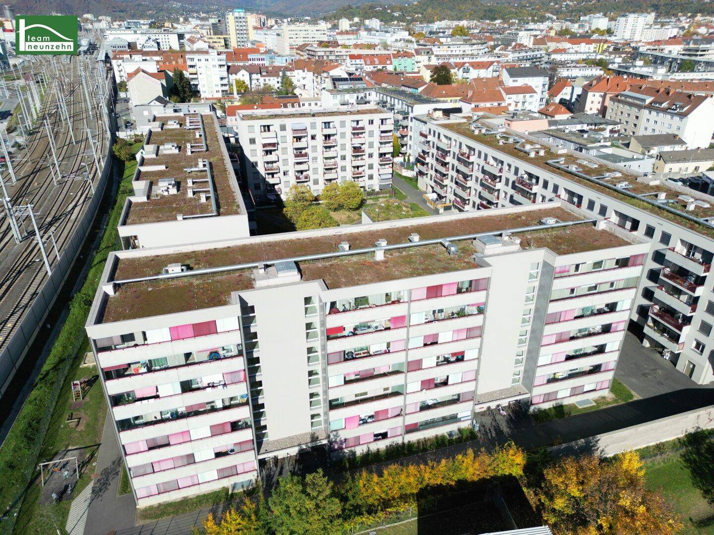 Luftaufnahme einer modernen Wohnanlage mit begrünten Dächern und städtischer Umgebung.