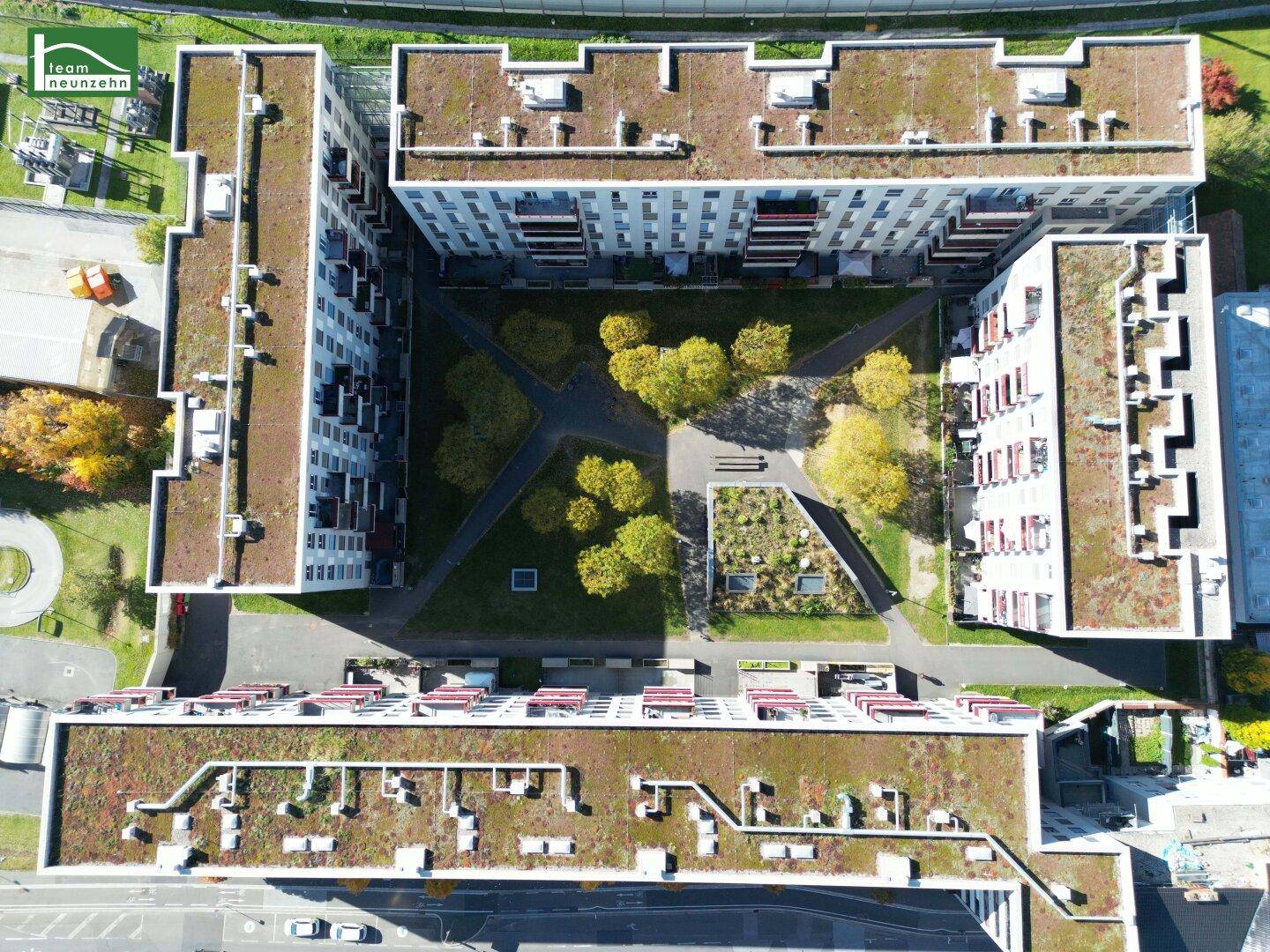 Draufsicht auf den begrünten Innenhof und die Flachdächer des Wohnkomplexes.