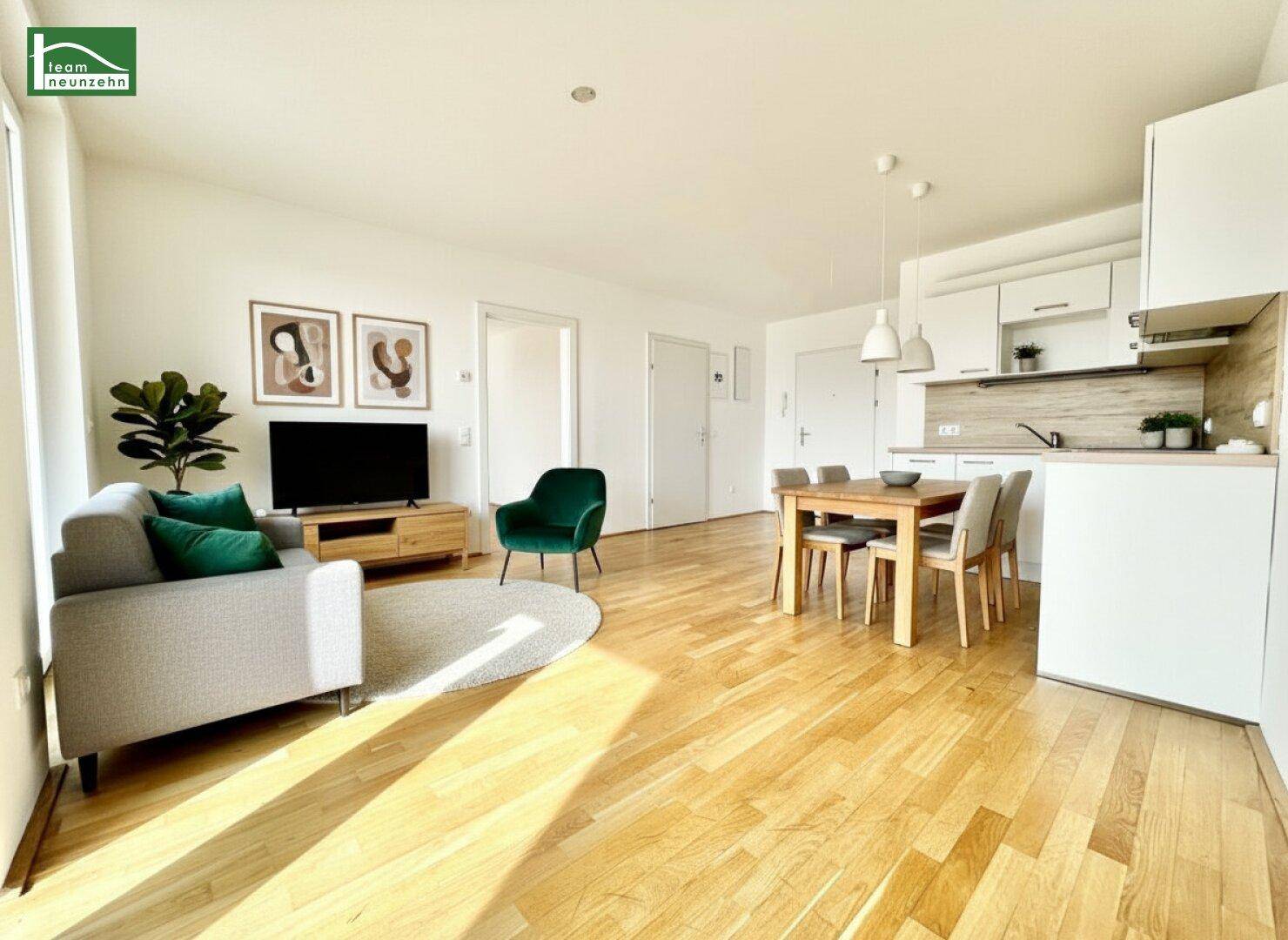 Helles, offenes Wohn-Esszimmer mit integrierter Küche, Parkettboden und moderner Einrichtung.