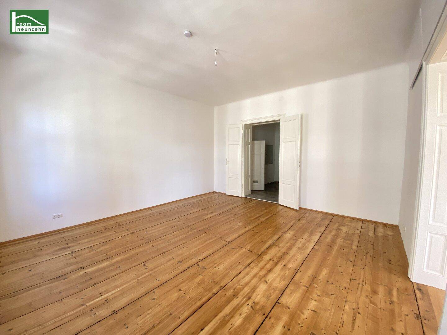 Geräumiger, leerer Raum mit hellem Holzboden und hohen Decken, bereit zur Einrichtung.