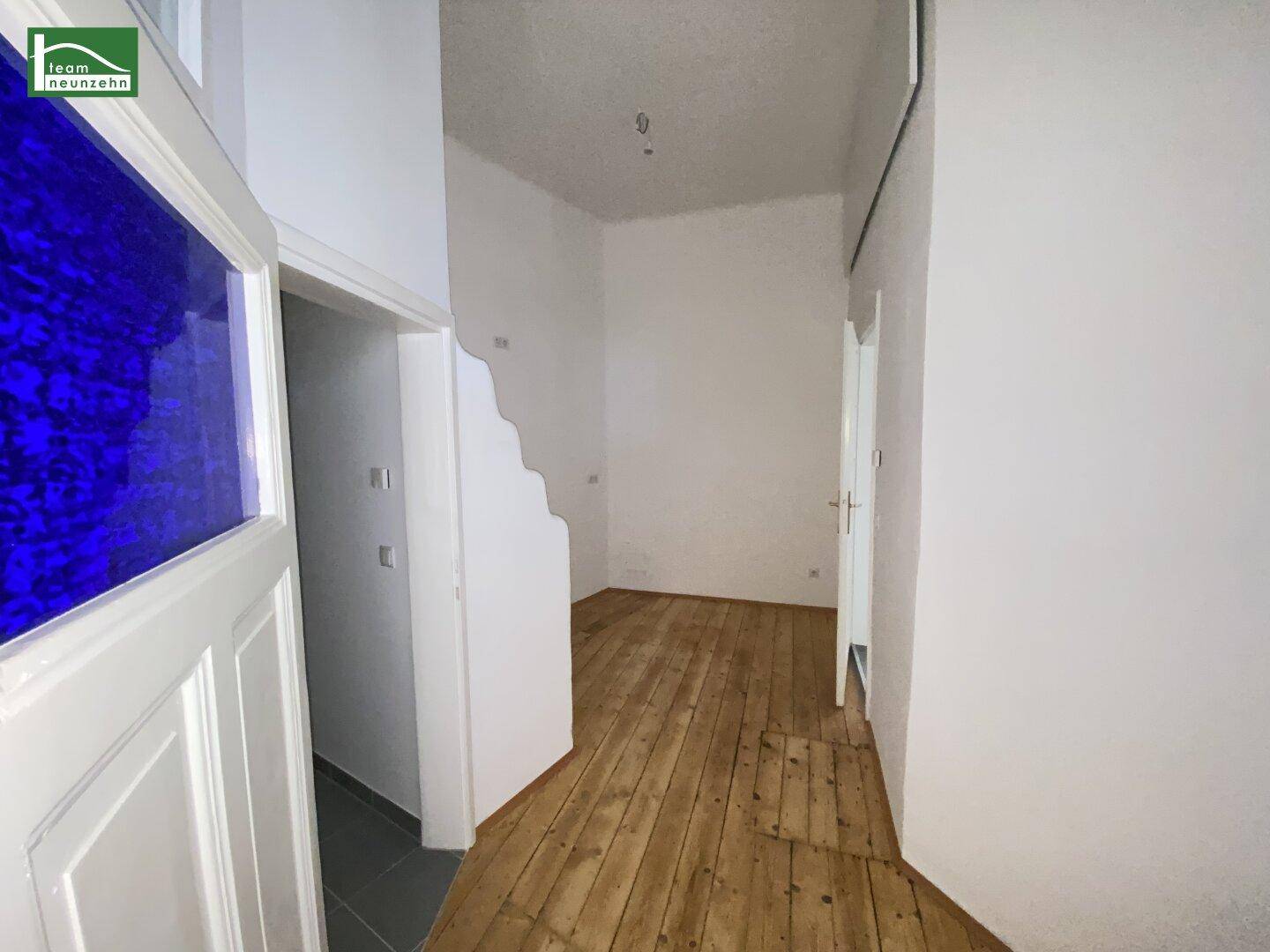 Weiterer Blick in den Raum mit Holzboden und dem Eingang zum angrenzenden Badezimmer.