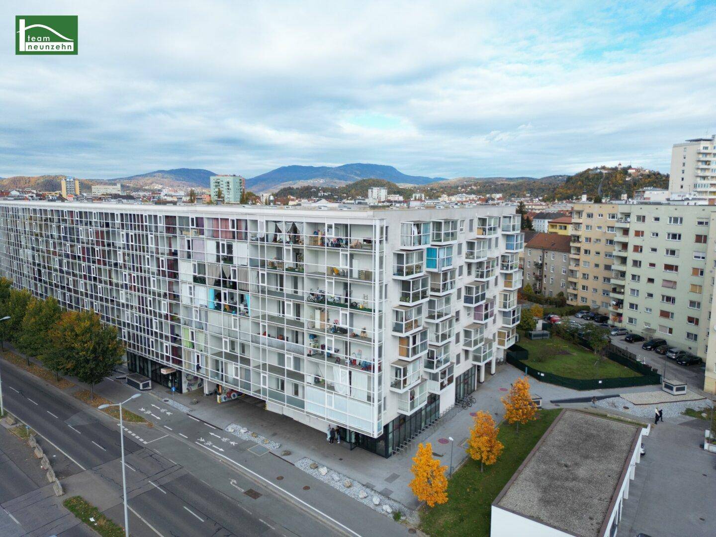 Moderne Wohnanlage mit zahlreichen Balkonen und urbaner Umgebung, umgeben von Grünflächen.