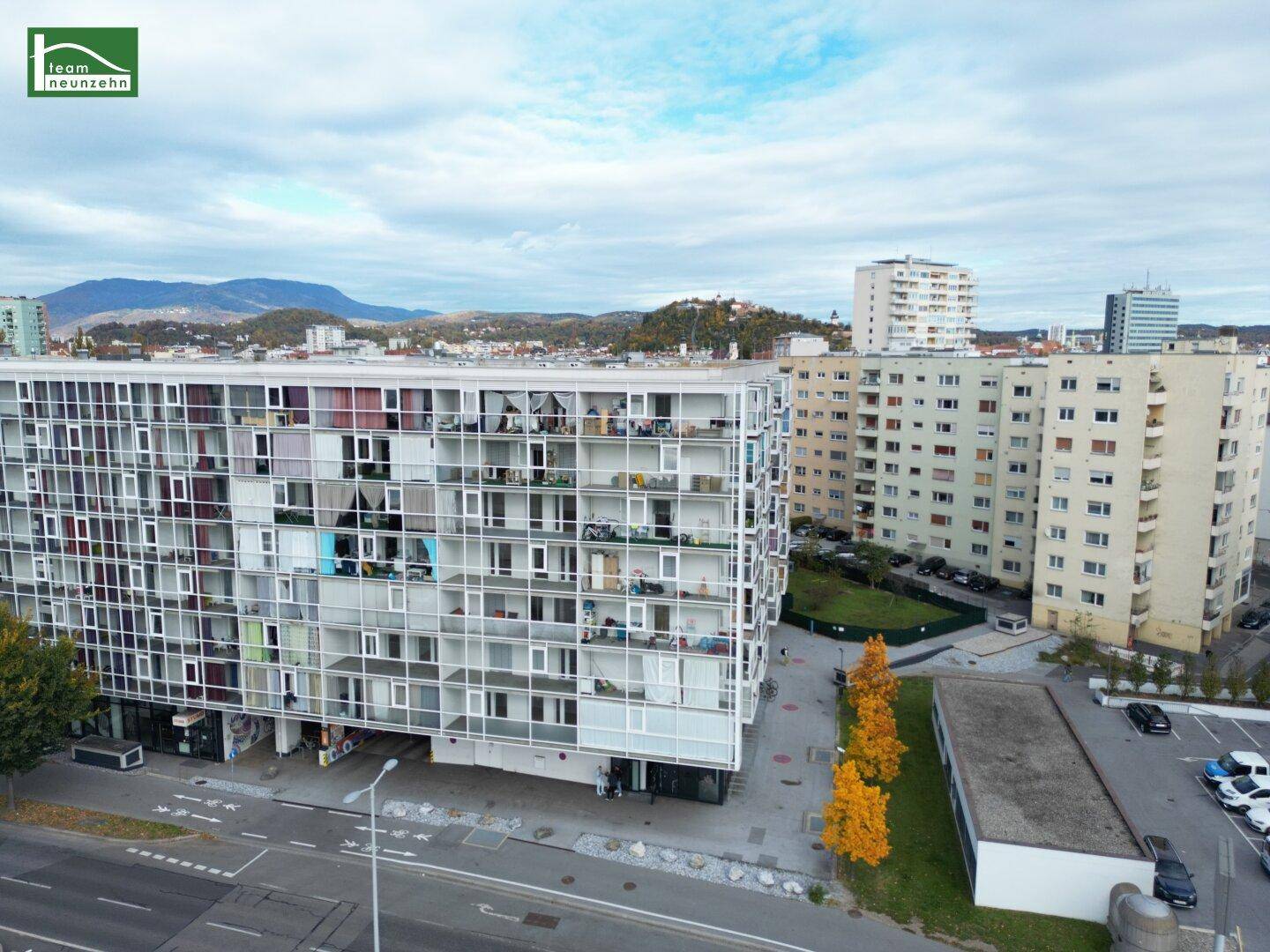 Luftaufnahme von modernen Wohngebäuden mit städtischer Umgebung und Bergen im Hintergrund.
