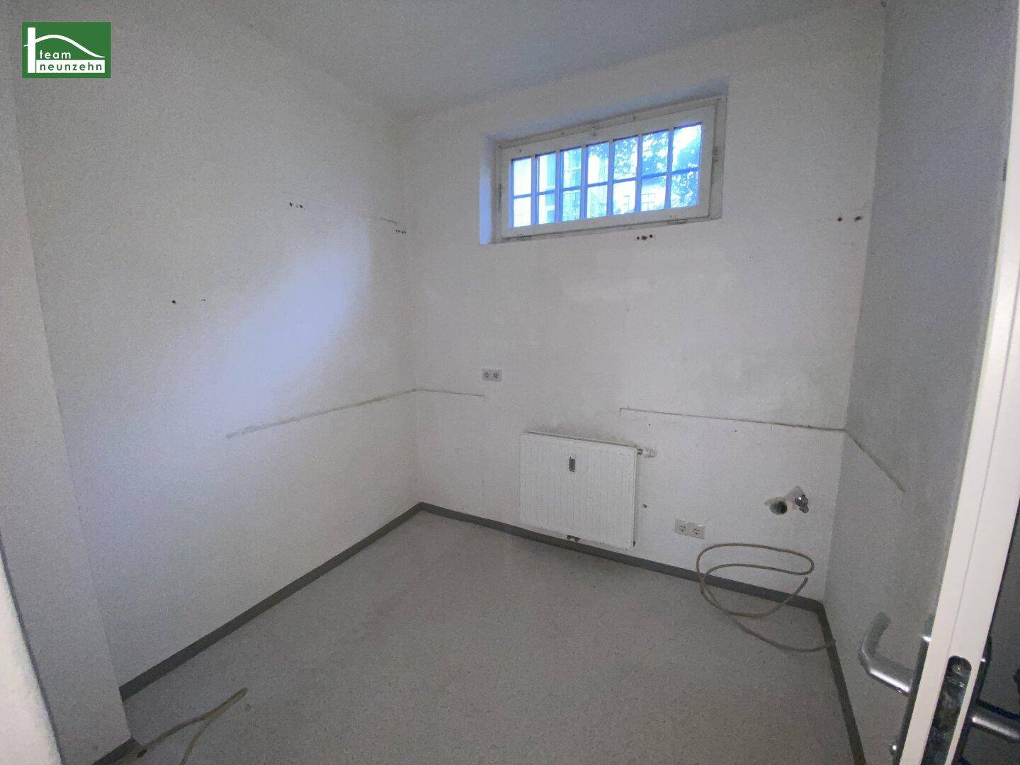 Kleiner Hauswirtschaftsraum mit Fenster, Heizkörper und Anschlüssen, bereit für die Installation von Geräten.