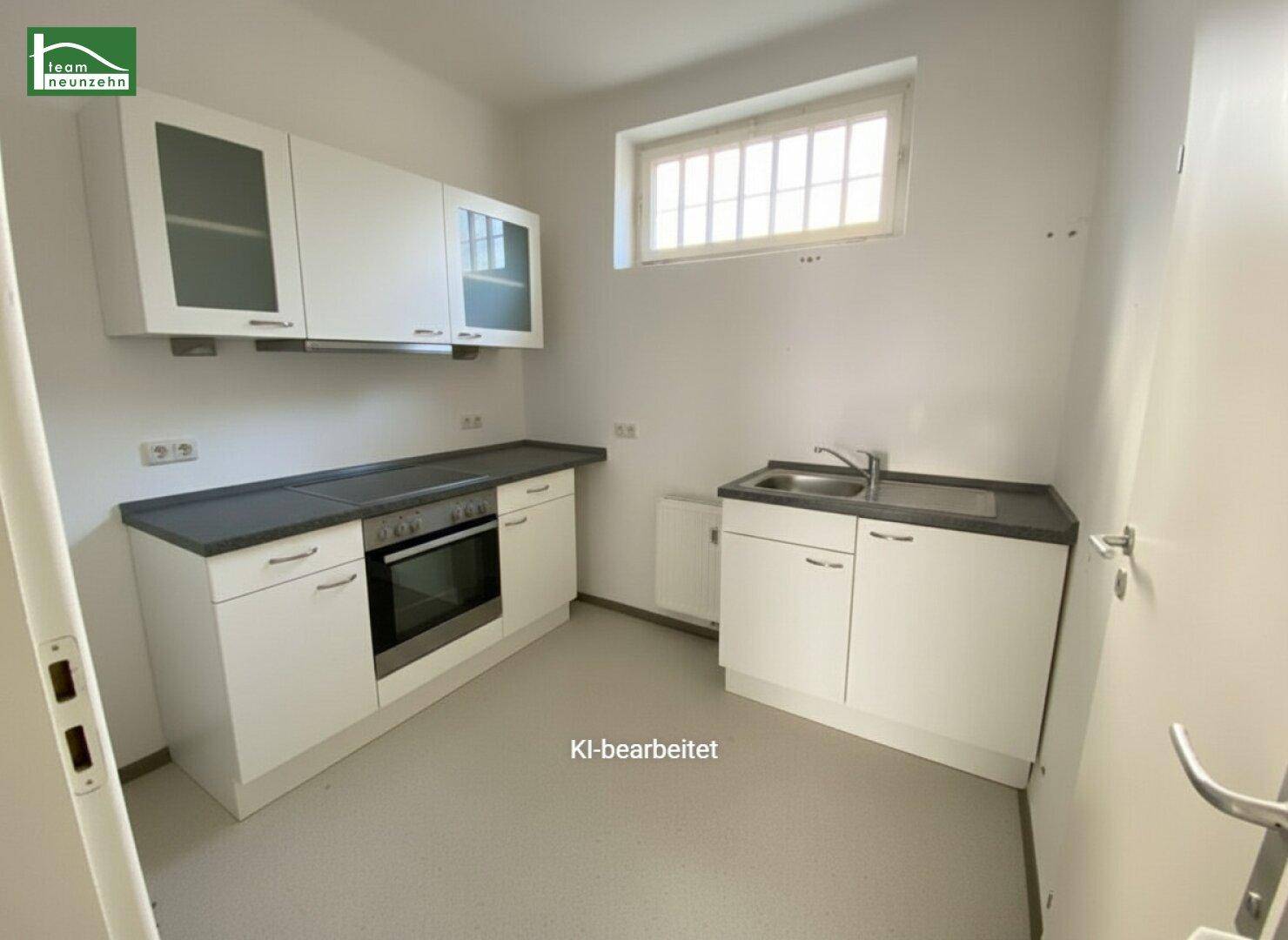 Funktionale Küchenzeile mit weißen Schränken, dunkler Arbeitsplatte, Spüle und integriertem Backofen.