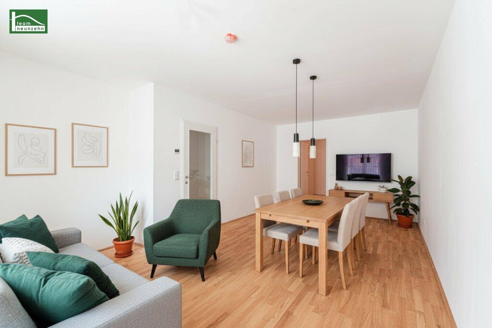 Helles Wohn- und Esszimmer mit Parkettboden, modernen Möbeln und Zugang zu weiteren Räumen.