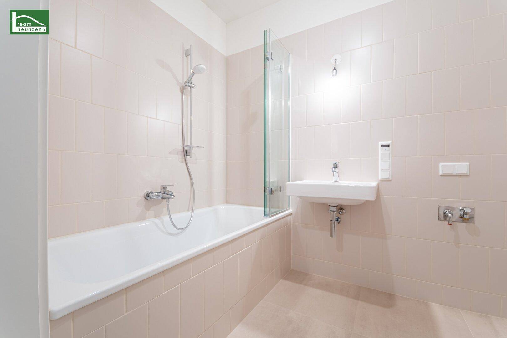 Helles Badezimmer mit Badewanne, Duschabtrennung und beigefarbenen Fliesen.