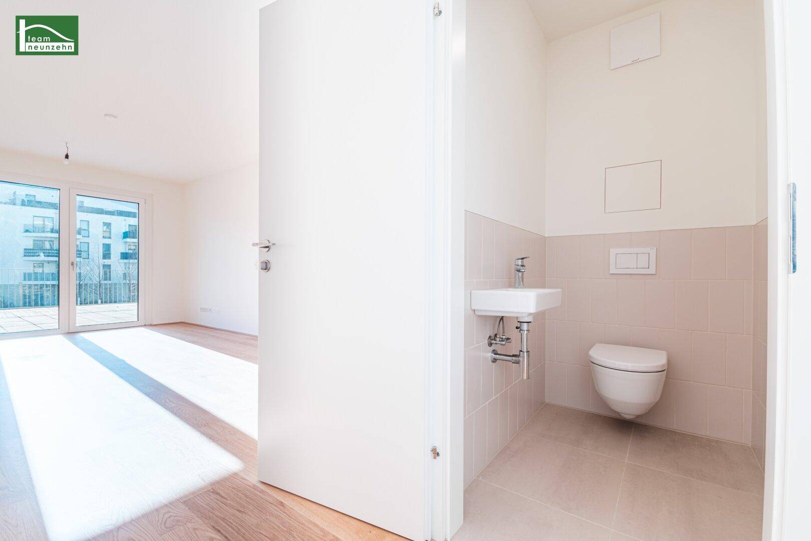 Kleines Gäste-WC mit wandhängender Toilette und Waschbecken, hell gefliest.