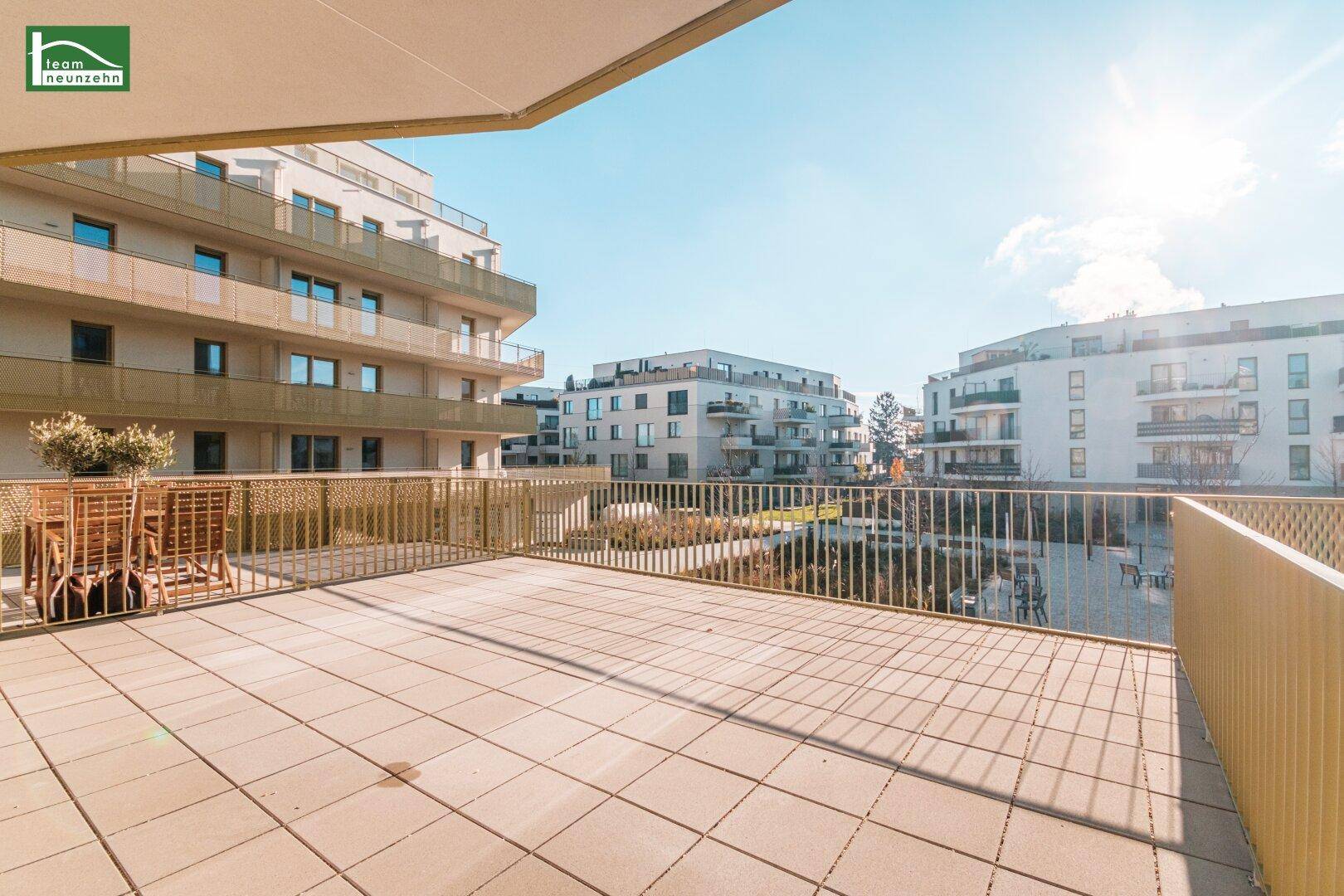 Geräumige Terrasse mit Sitzgelegenheiten und weitem Blick über die Wohnanlage.