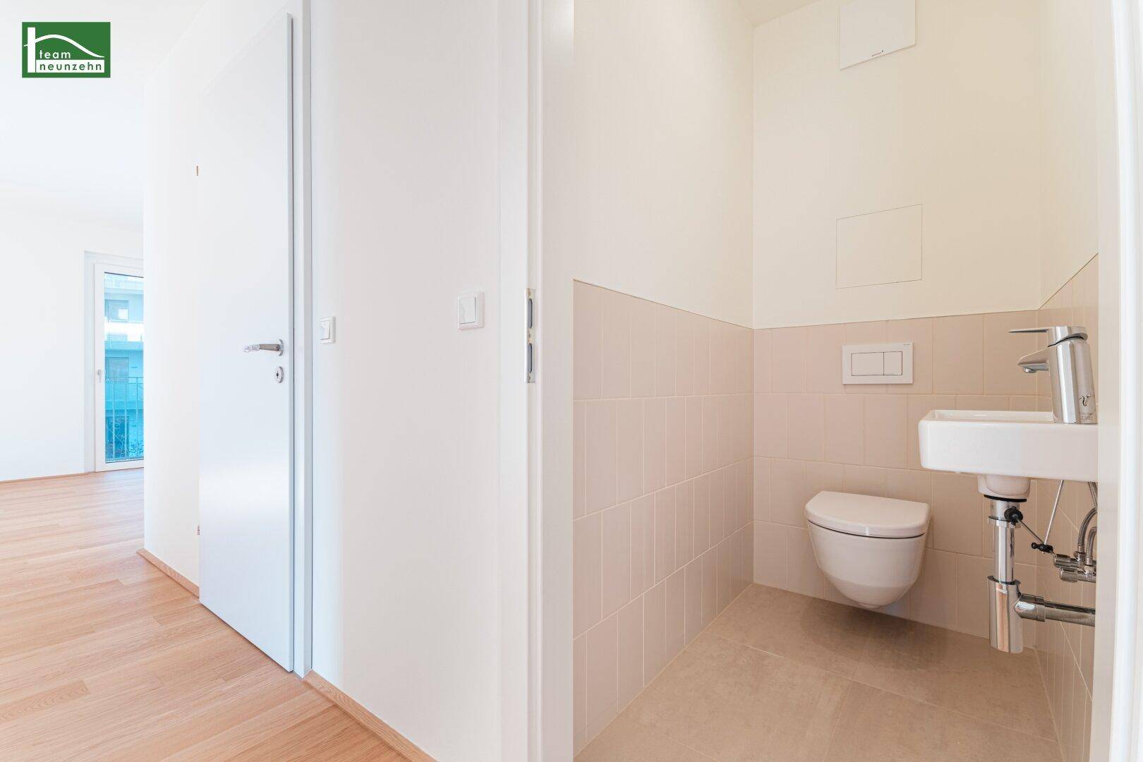 Separates Gäste-WC mit wandhängender Toilette und kleinem Waschbecken.