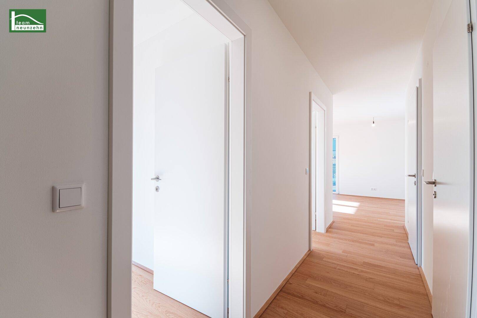 Heller Flur mit Holzboden und mehreren Türen, der verschiedene Räume verbindet.
