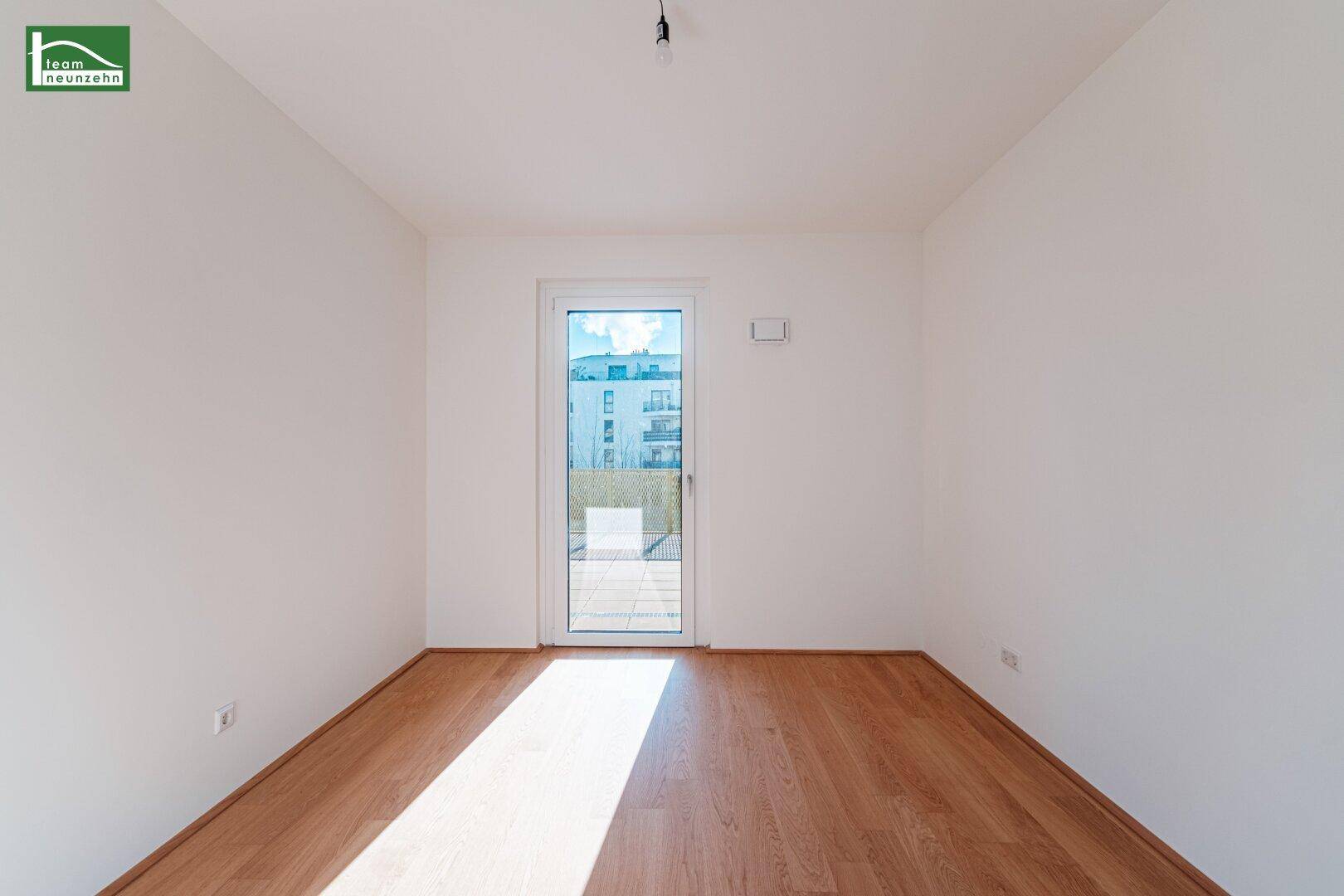 Leeres, helles Zimmer mit Holzboden und Zugang zu einem Außenbereich, ideal als Kinderzimmer.