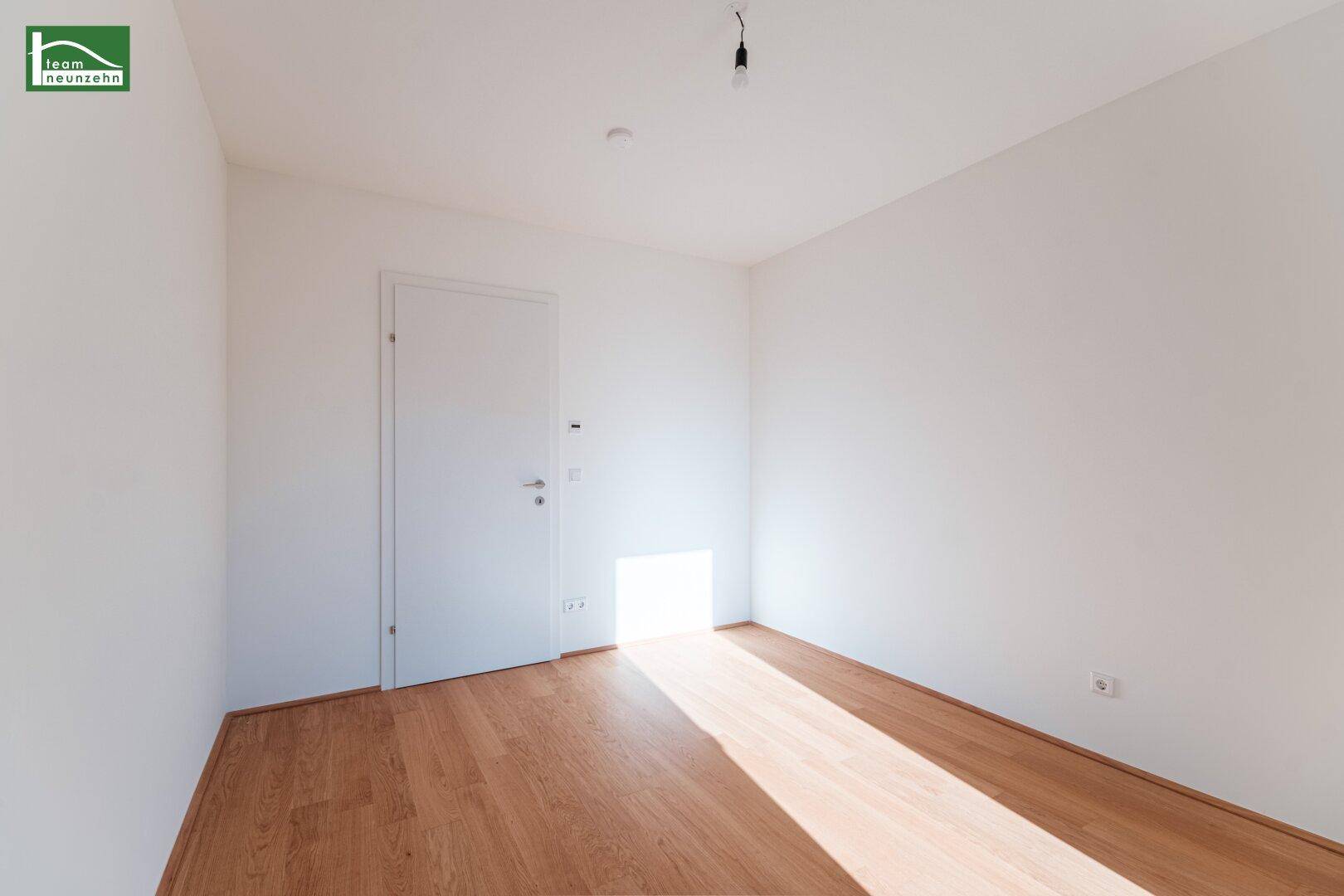 Helles, leeres Zimmer mit Holzboden und weiß gestrichenen Wänden, vielseitig nutzbar.