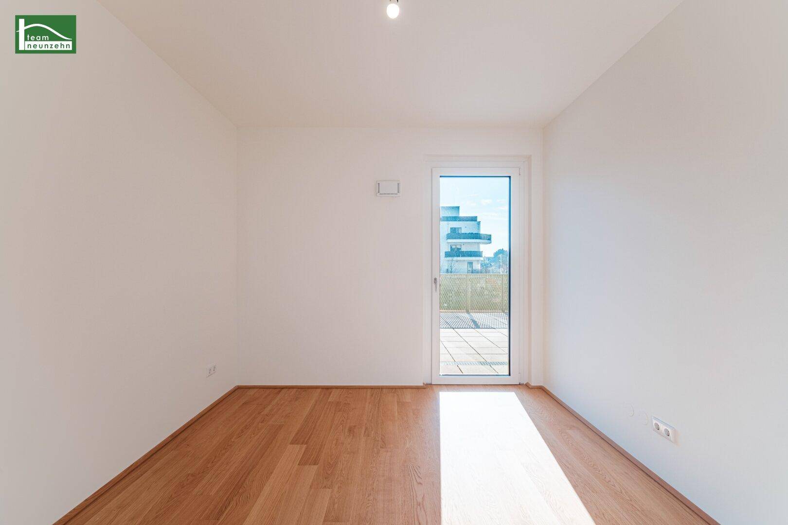 Helles, leeres Zimmer mit Holzboden und Zugang zu einem Außenbereich, ideal als Schlafzimmer.