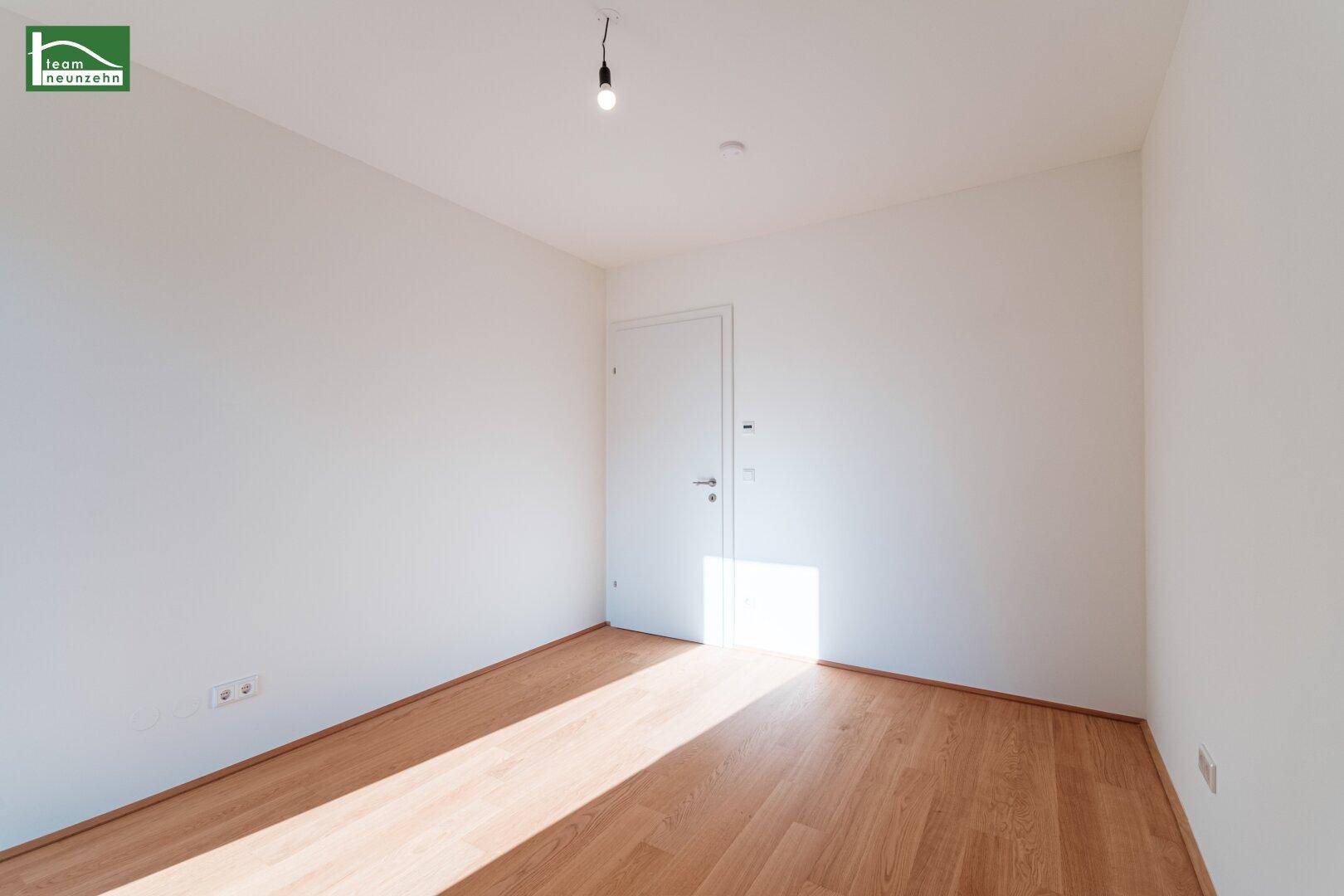 Leeres Zimmer mit Holzboden und weiß gestrichenen Wänden, bereit zur individuellen Gestaltung.