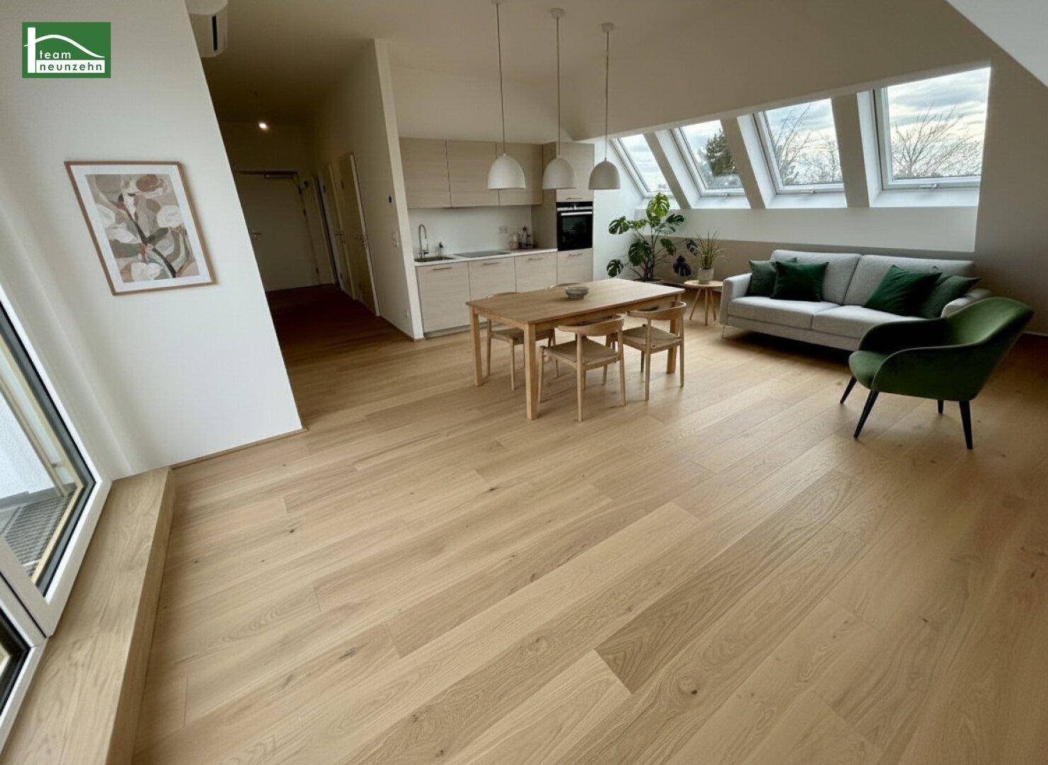 Offener Wohn-Essbereich mit integrierter Küche, Holzboden und Dachfenstern.