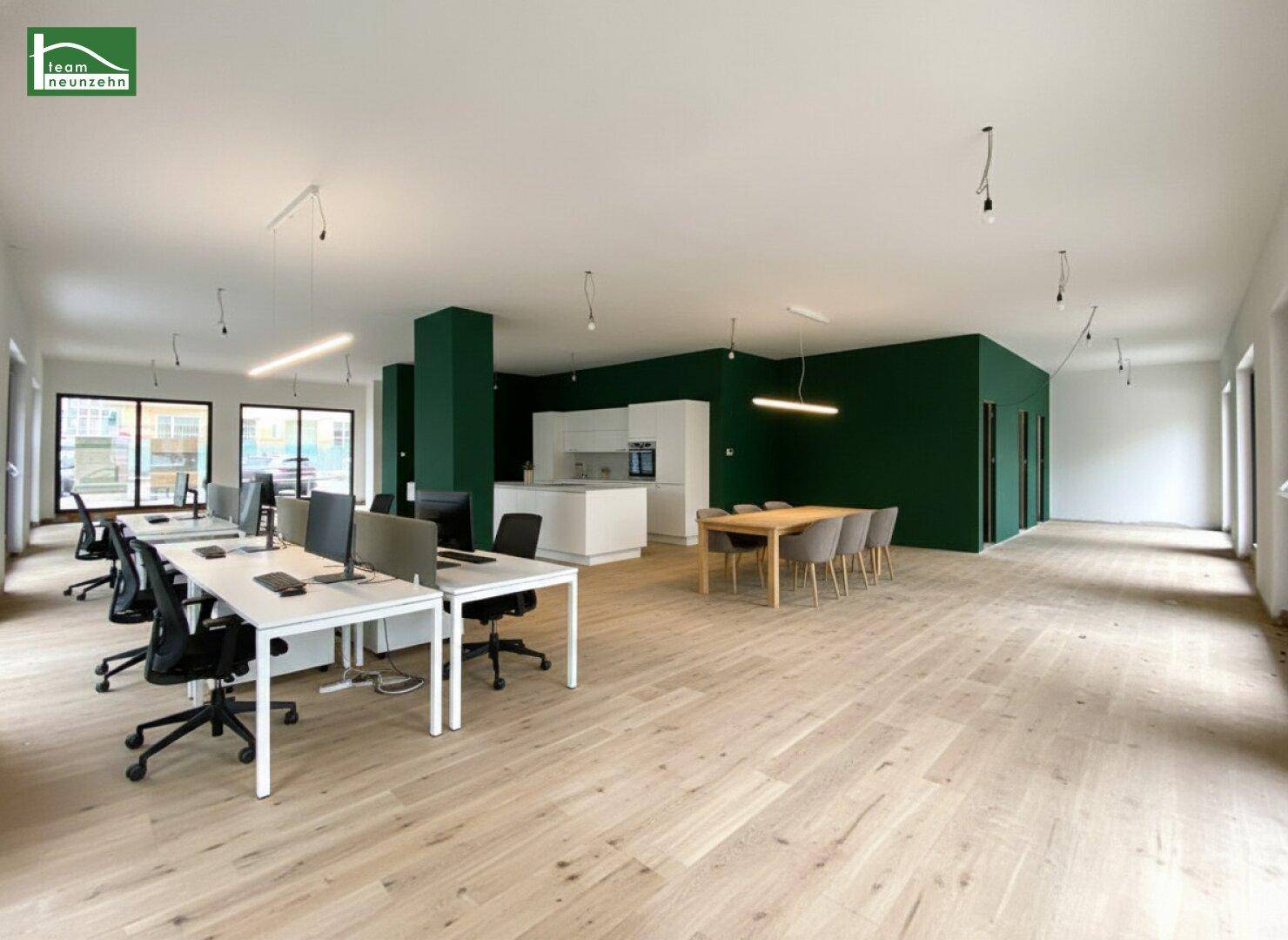 Helles Büro mit Holzboden, grünen Wänden und moderner Einrichtung, inklusive Küchenbereich.