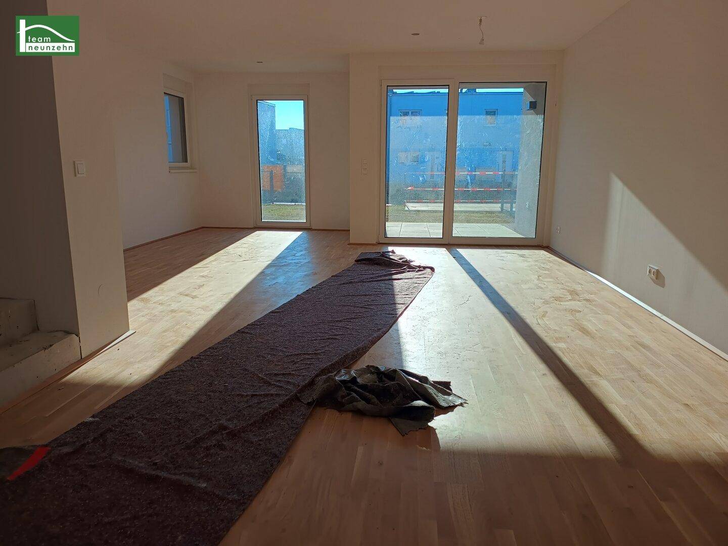 Geräumiger, heller Wohnbereich mit Holzboden und großen Fenstern zum Garten.