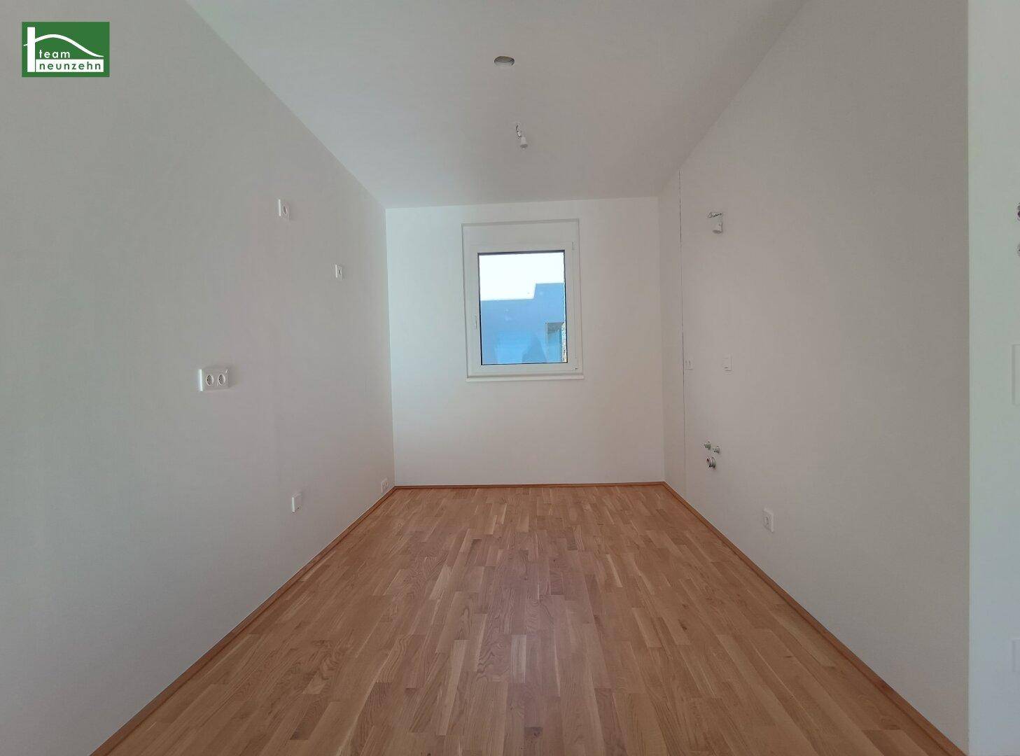 Helles Schlafzimmer mit Holzboden und einem Fenster, ideal für ein Kinder- oder Gästezimmer.