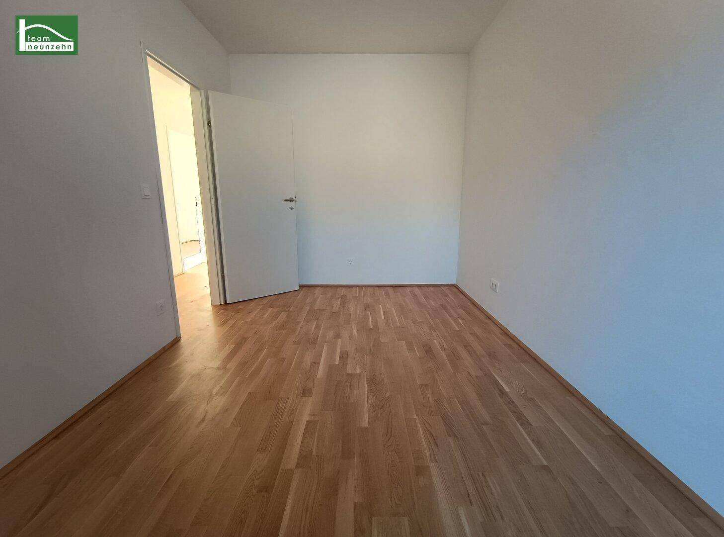 Leeres Zimmer mit Holzboden und weiß gestrichenen Wänden, ideal als Schlaf- oder Arbeitszimmer.