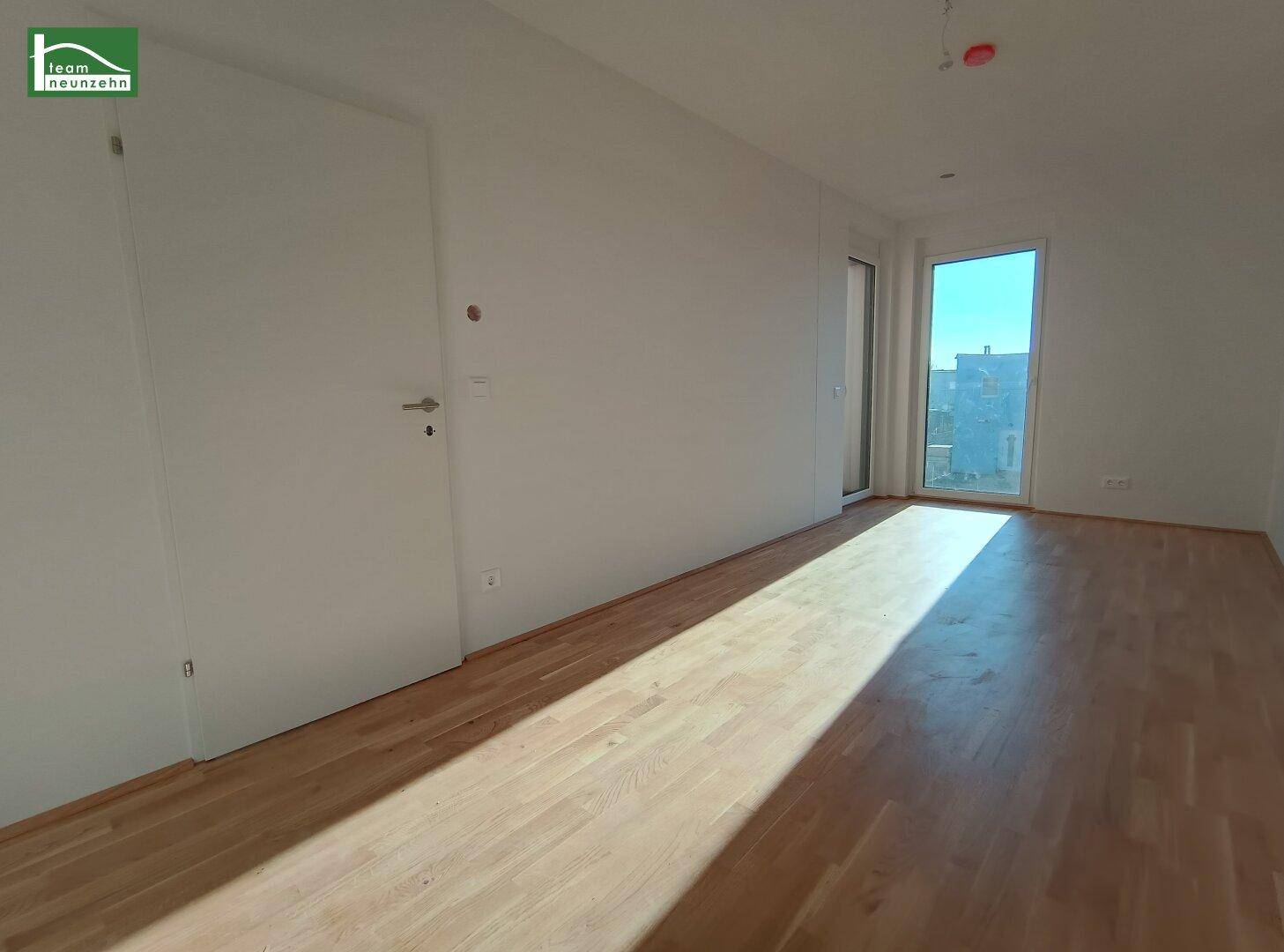 Lichtdurchfluteter Wohnbereich mit Holzboden und großen Fenstern, bereit zur Gestaltung.