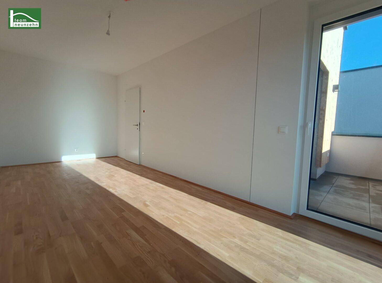 Geräumiger, heller Wohnbereich mit Holzboden und Zugang zu einem Außenbereich.