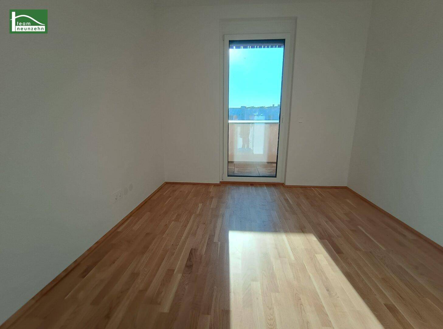 Helles Zimmer mit Holzboden und Zugang zu einem französischen Balkon, ideal als Schlafzimmer.