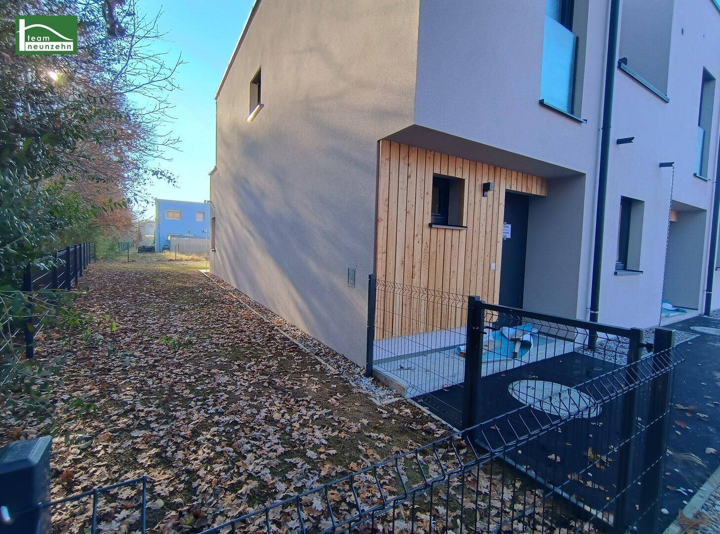 Seitenansicht eines modernen Reihenhauses mit Holzelementen und Gartenbereich.