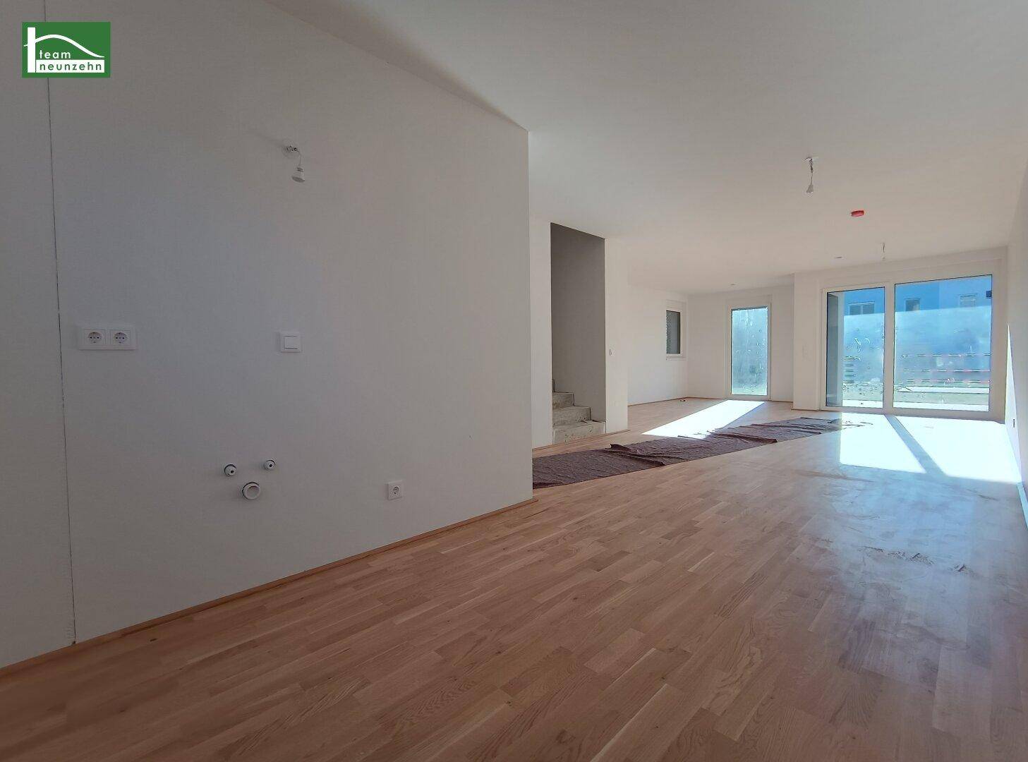 Weitläufiger Wohnbereich mit Parkettboden und großen Fensterfronten für viel Helligkeit.