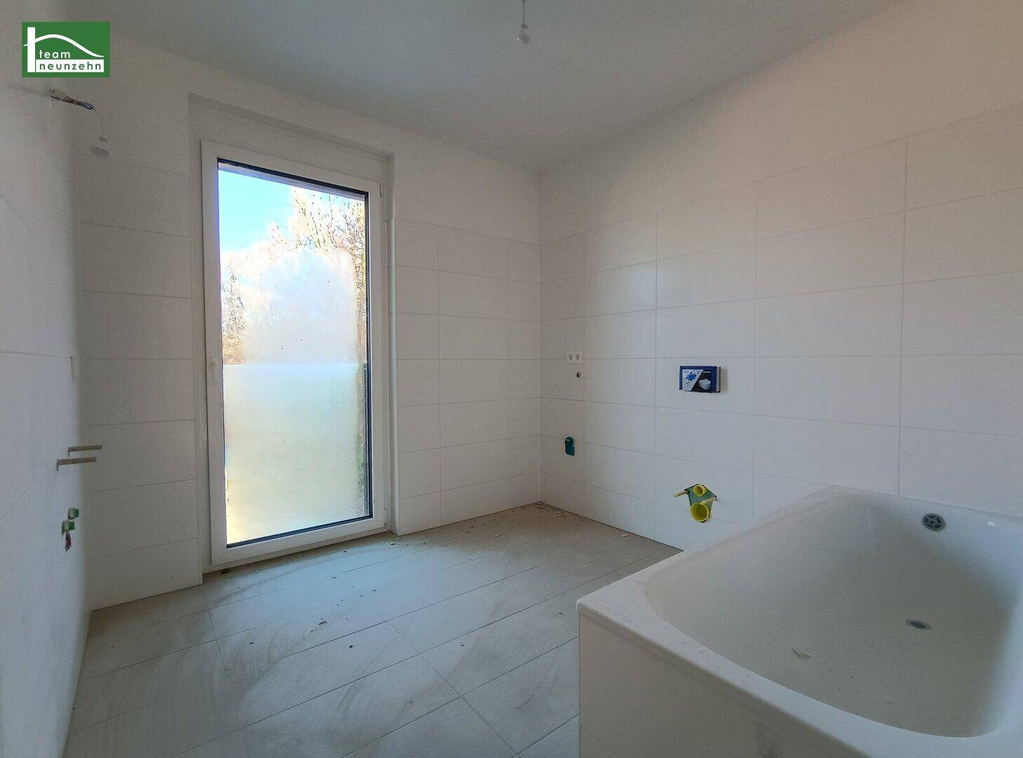 Unfertiges Badezimmer mit Badewanne und Fenster, bereit für den Ausbau.