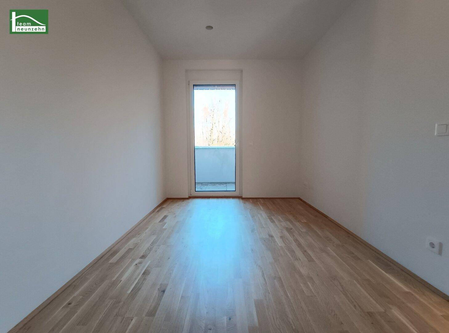 Helles Zimmer mit Parkettboden und Zugang zu einem Balkon, ideal für ein Schlafzimmer.