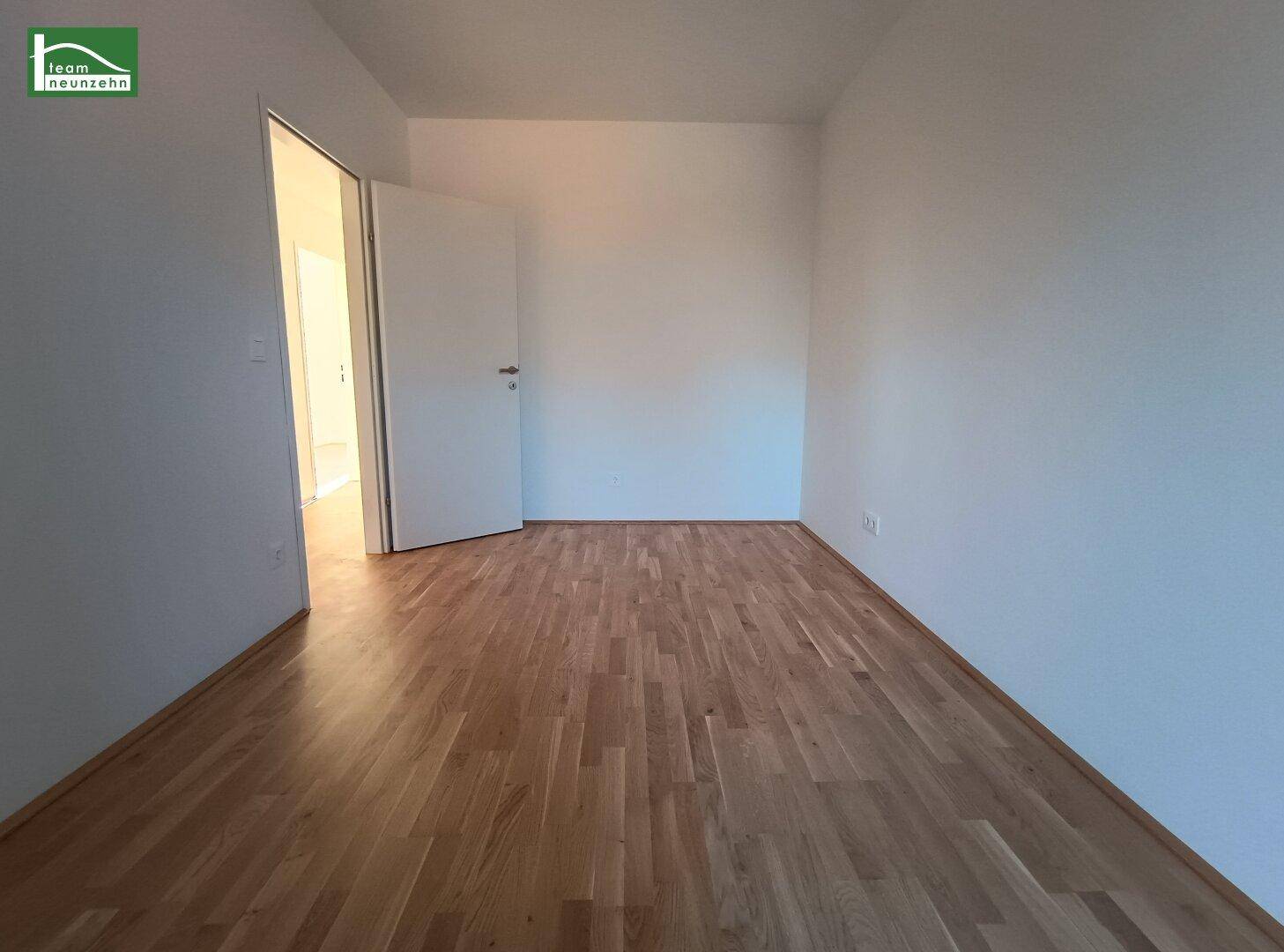 Freundliches Zimmer mit Parkettboden und weiß gestrichenen Wänden, ideal als Schlafzimmer.