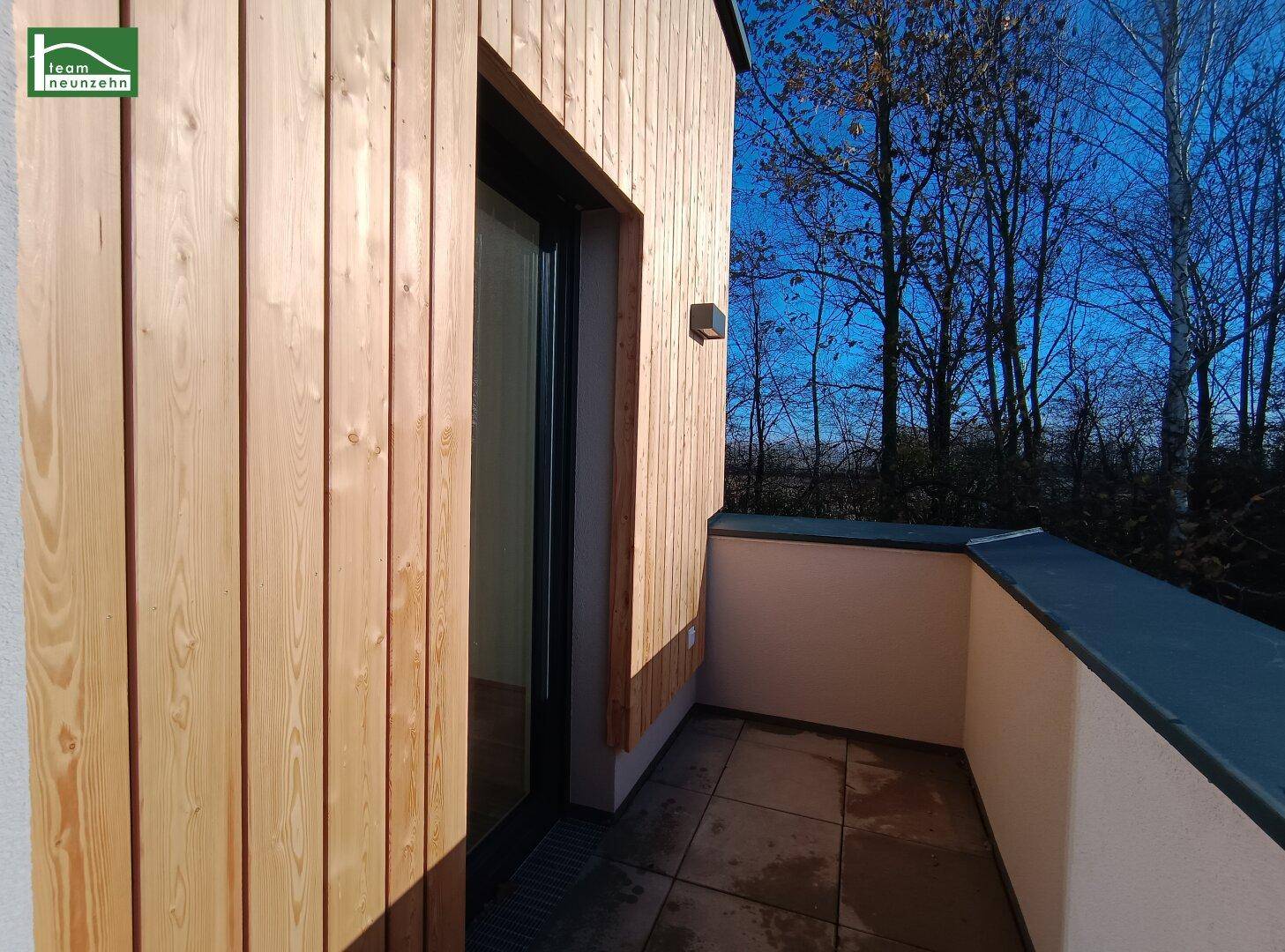 Kleiner Balkon mit Holzverkleidung und Fliesenboden, ideal für sonnige Stunden.