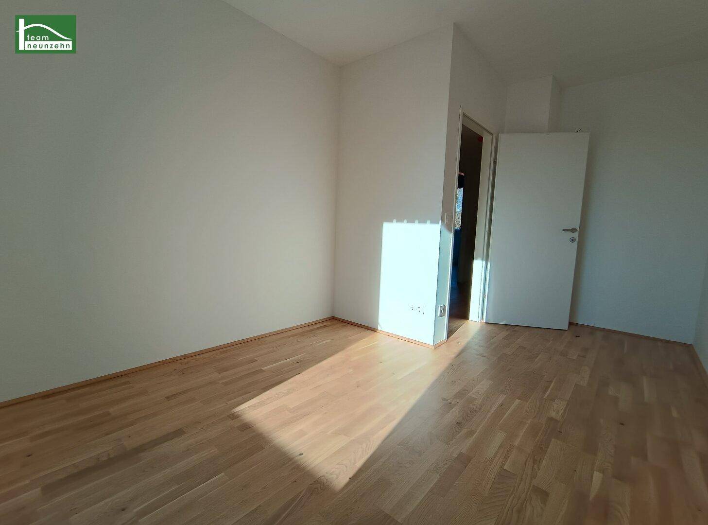 Leeres Zimmer mit Parkettboden und weiß gestrichenen Wänden, bereit zum Einzug.