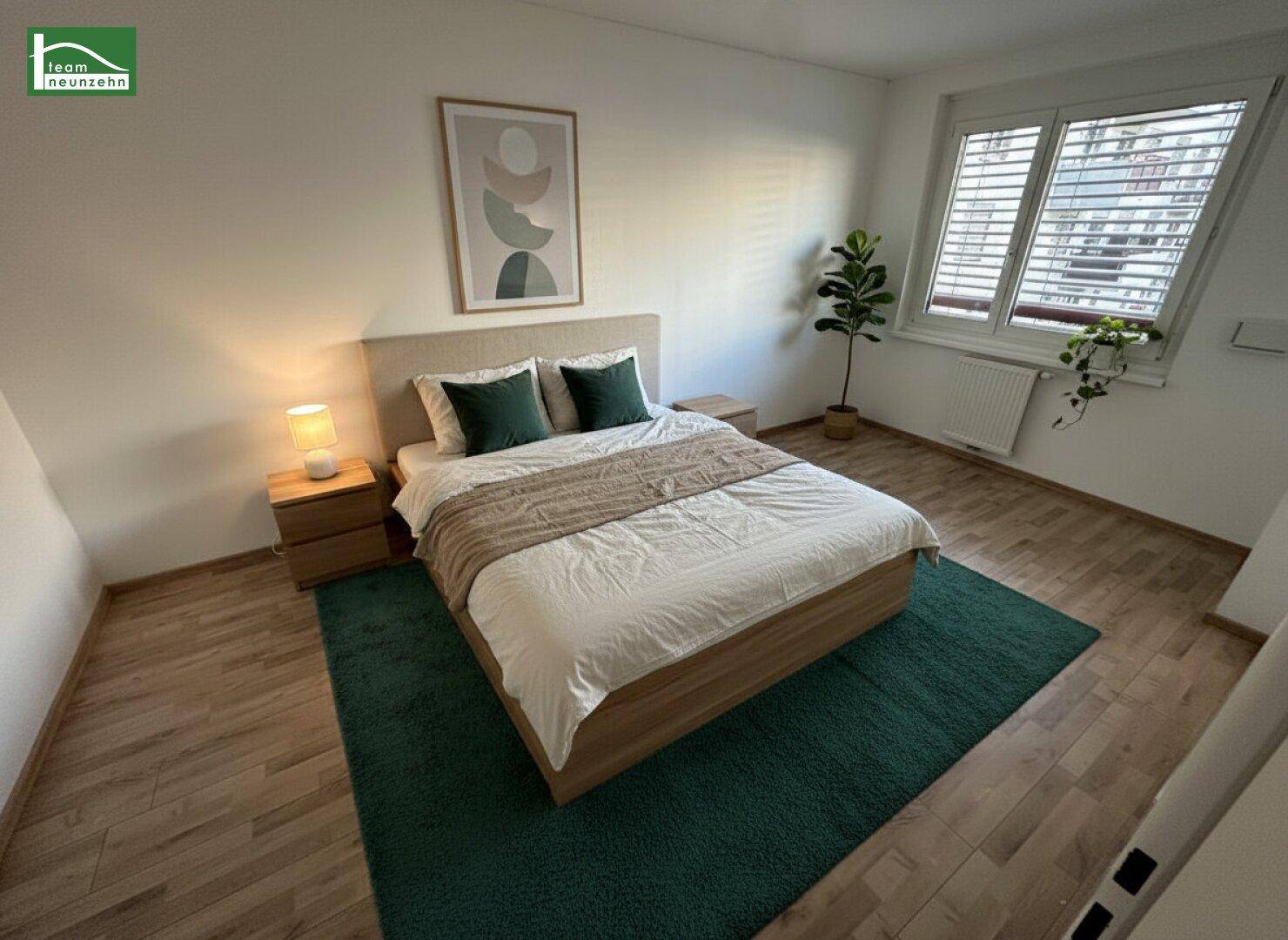 Gemütliches Schlafzimmer mit Holzboden, großem Fenster und einem grünen Teppich.