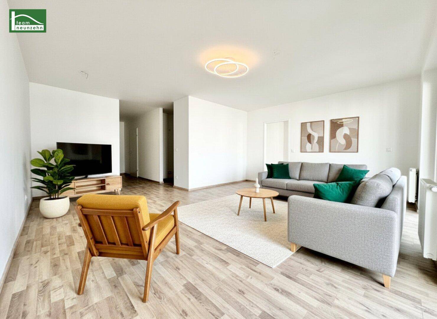 Helles und modern eingerichtetes Wohnzimmer mit hellem Holzboden, bequemen grauen Sofas und einem gelben Sessel.