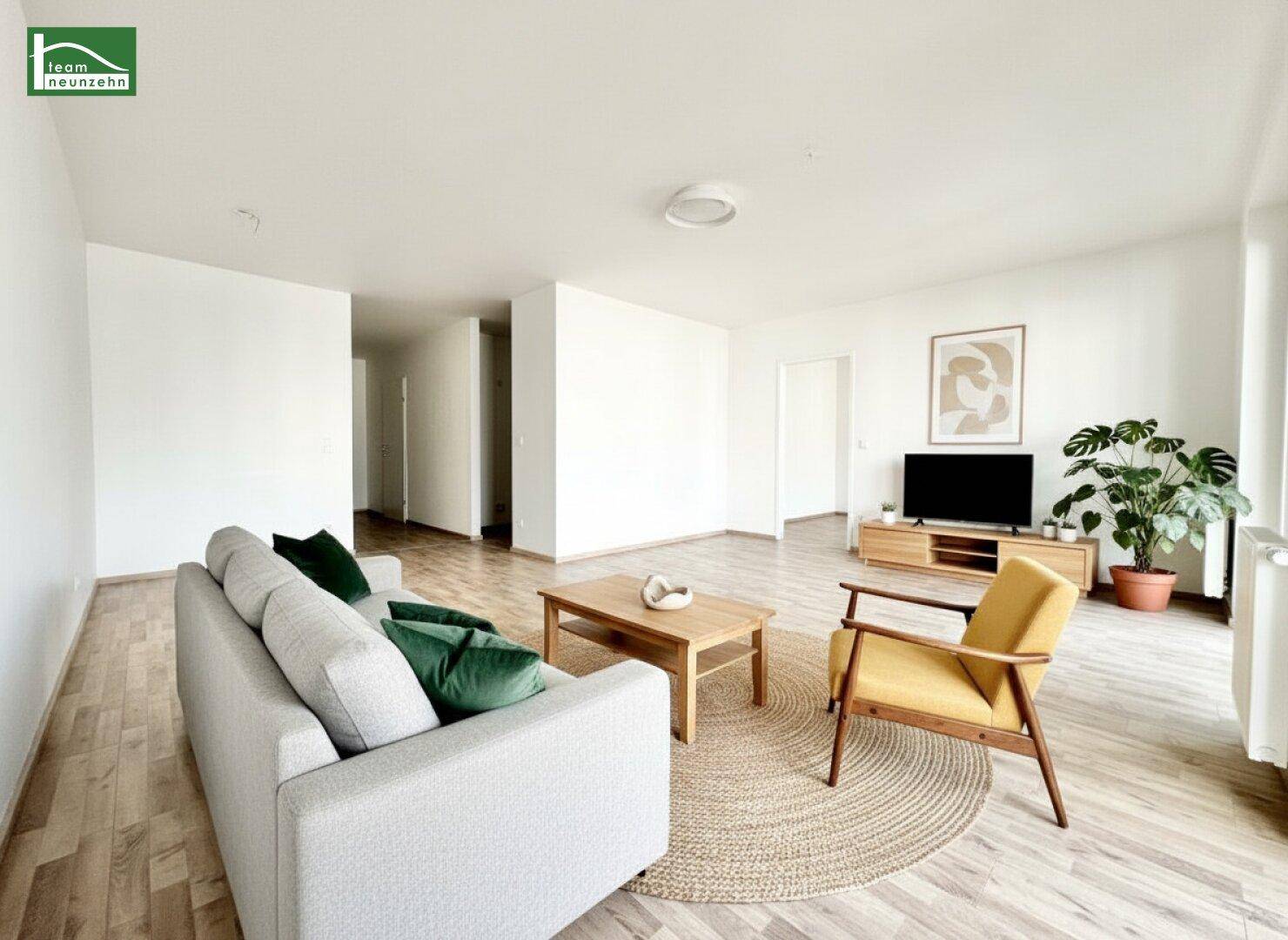 Modern eingerichtetes Wohnzimmer mit Laminatboden, Sofa und Sessel, ideal zum Entspannen.