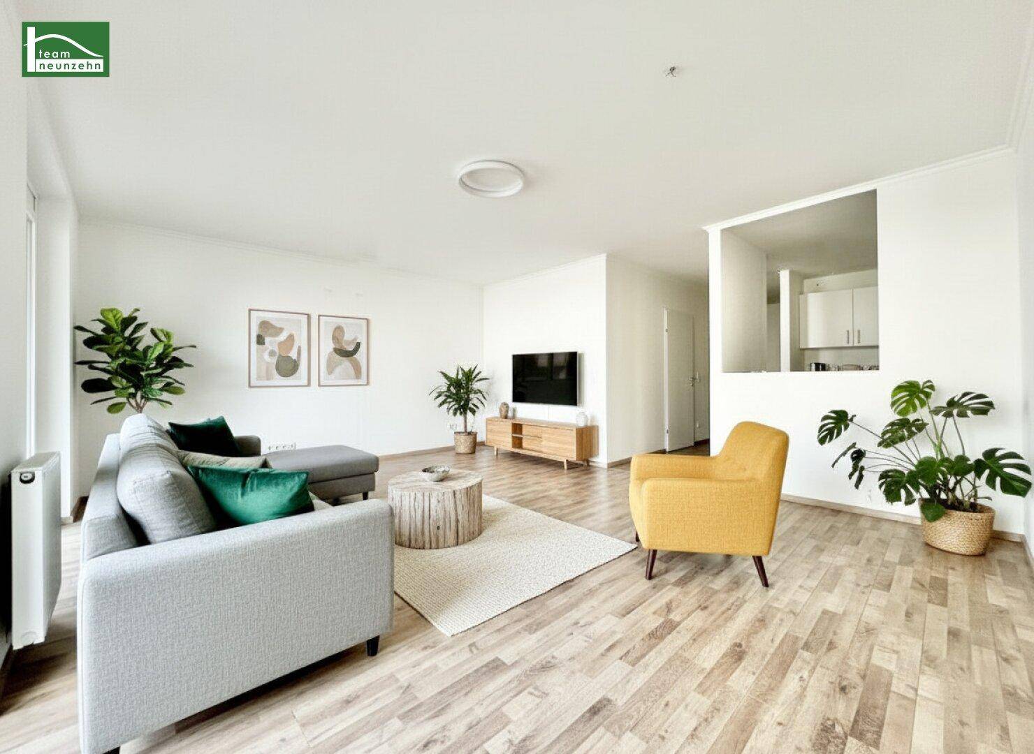 Helles Wohnzimmer mit modernem Interieur, Laminatboden und offener Verbindung zur Küche.
