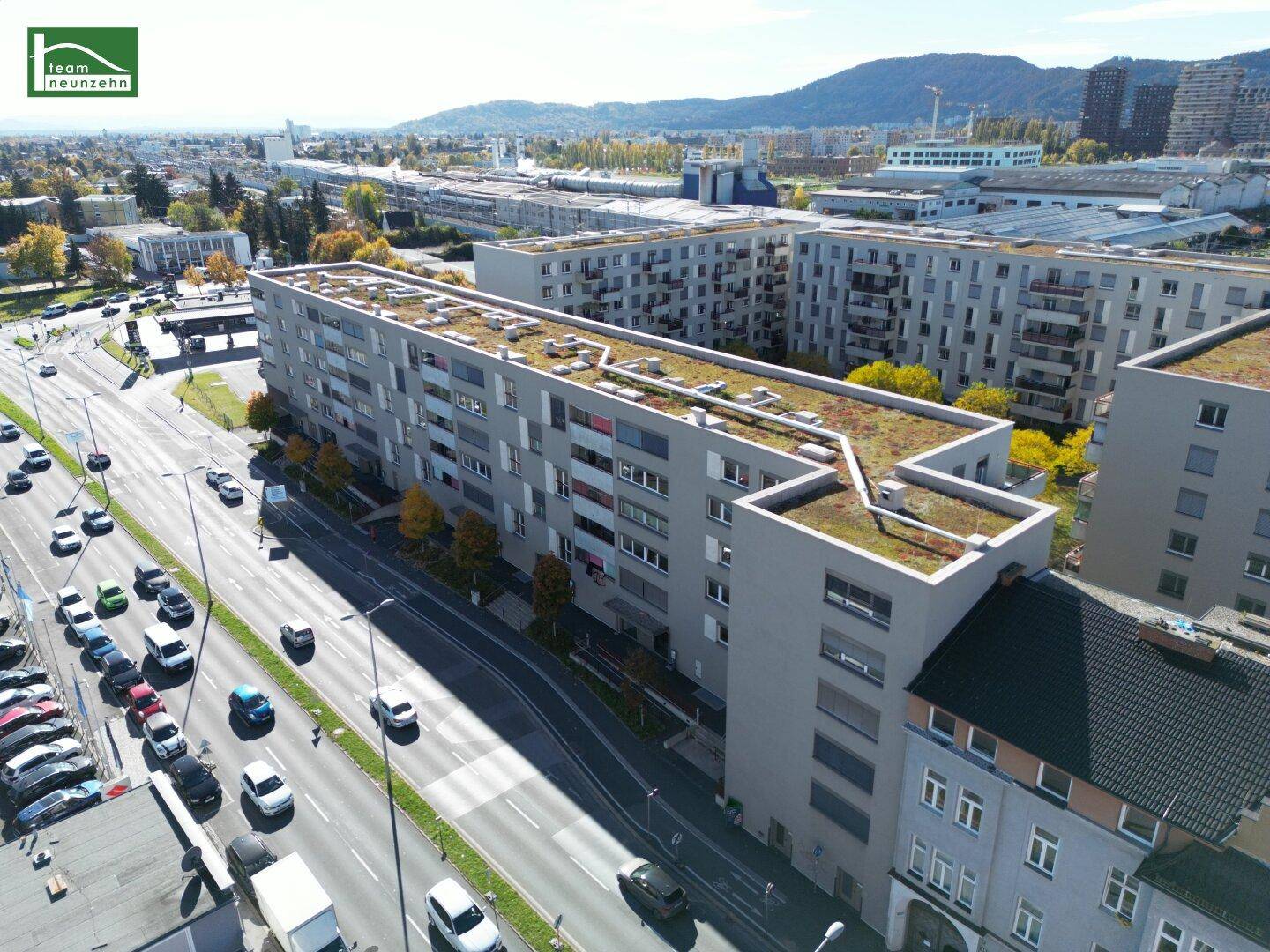 Luftaufnahme eines modernen Wohnkomplexes mit begrünten Dächern und städtischer Umgebung.
