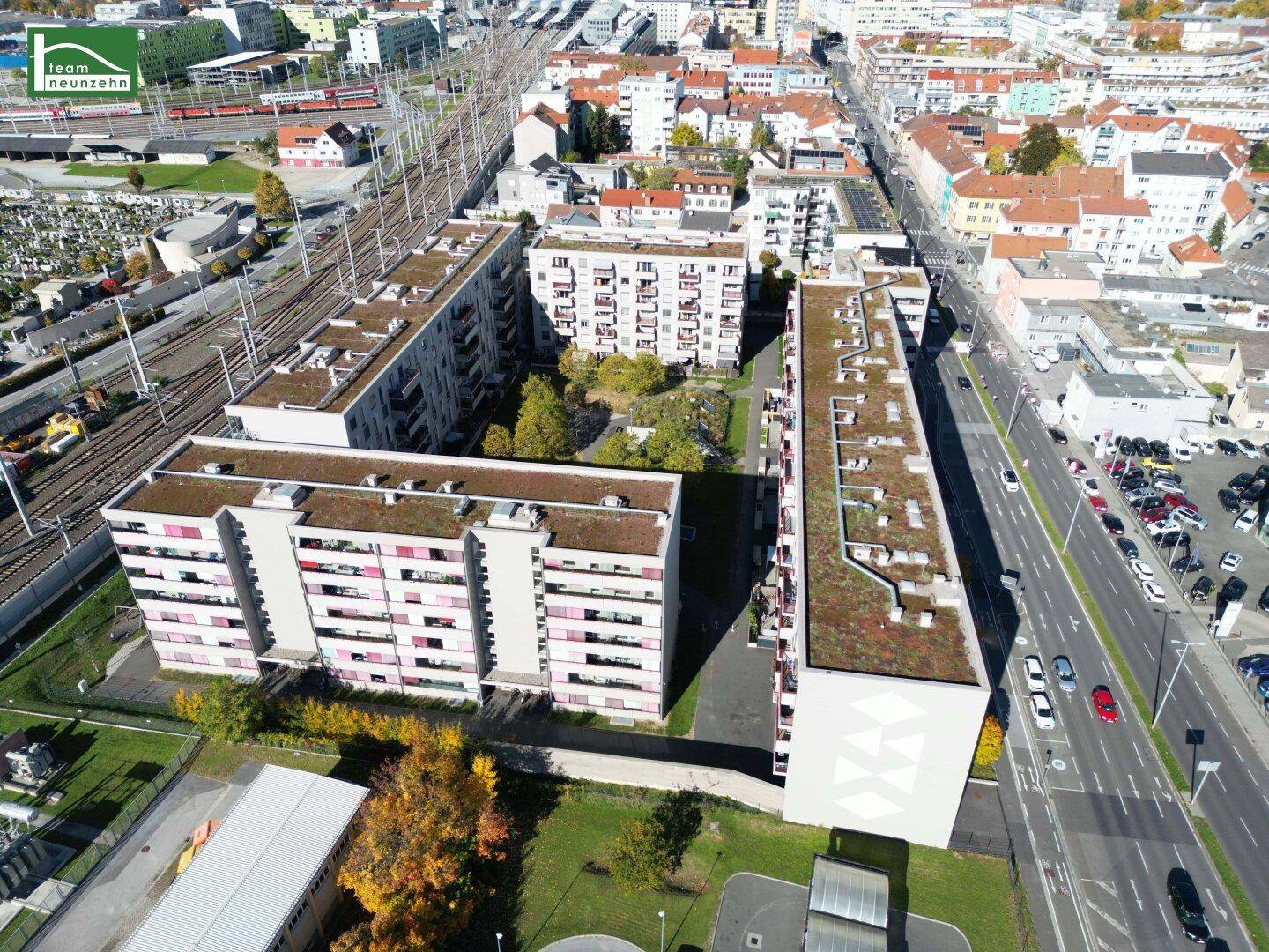 Vogelperspektive auf einen Wohnkomplex mit begrünten Dächern und umliegender Infrastruktur.