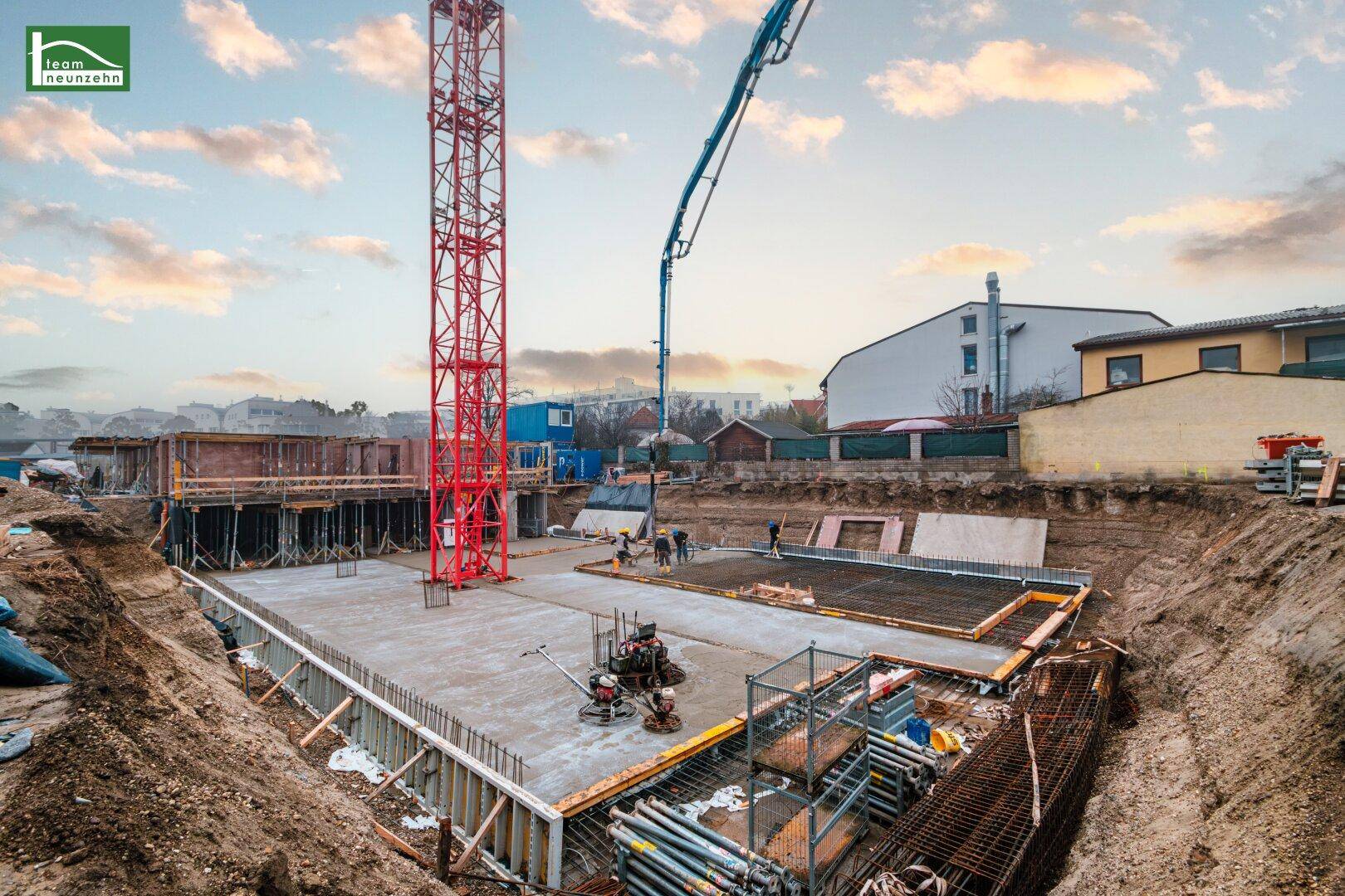 Baustelle des neuen Wohngebäudes mit Fundamentarbeiten und Kran.