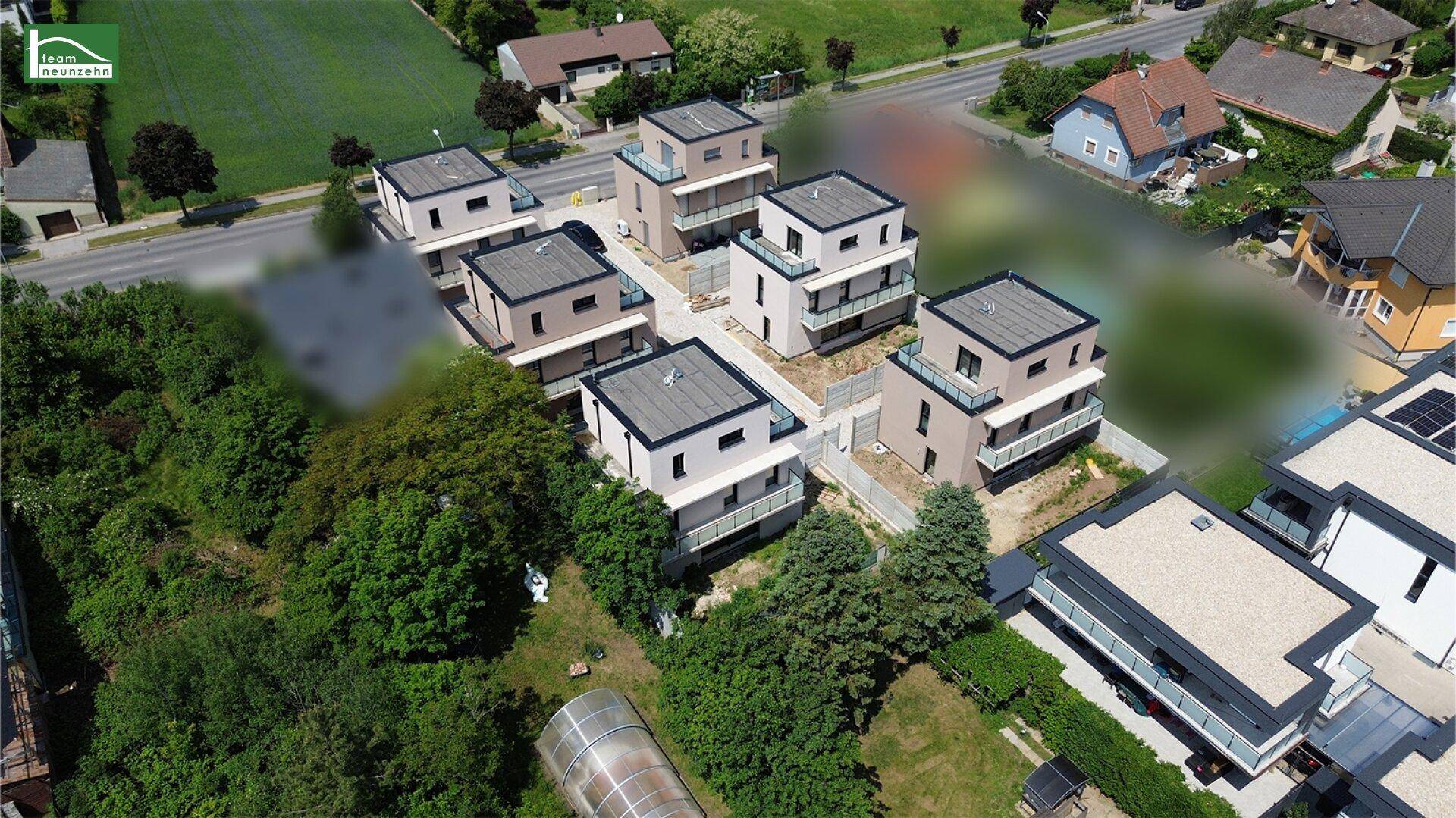 Übersicht über eine Gruppe von Neubauten mit moderner Architektur und Flachdächern in ländlicher Umgebung.