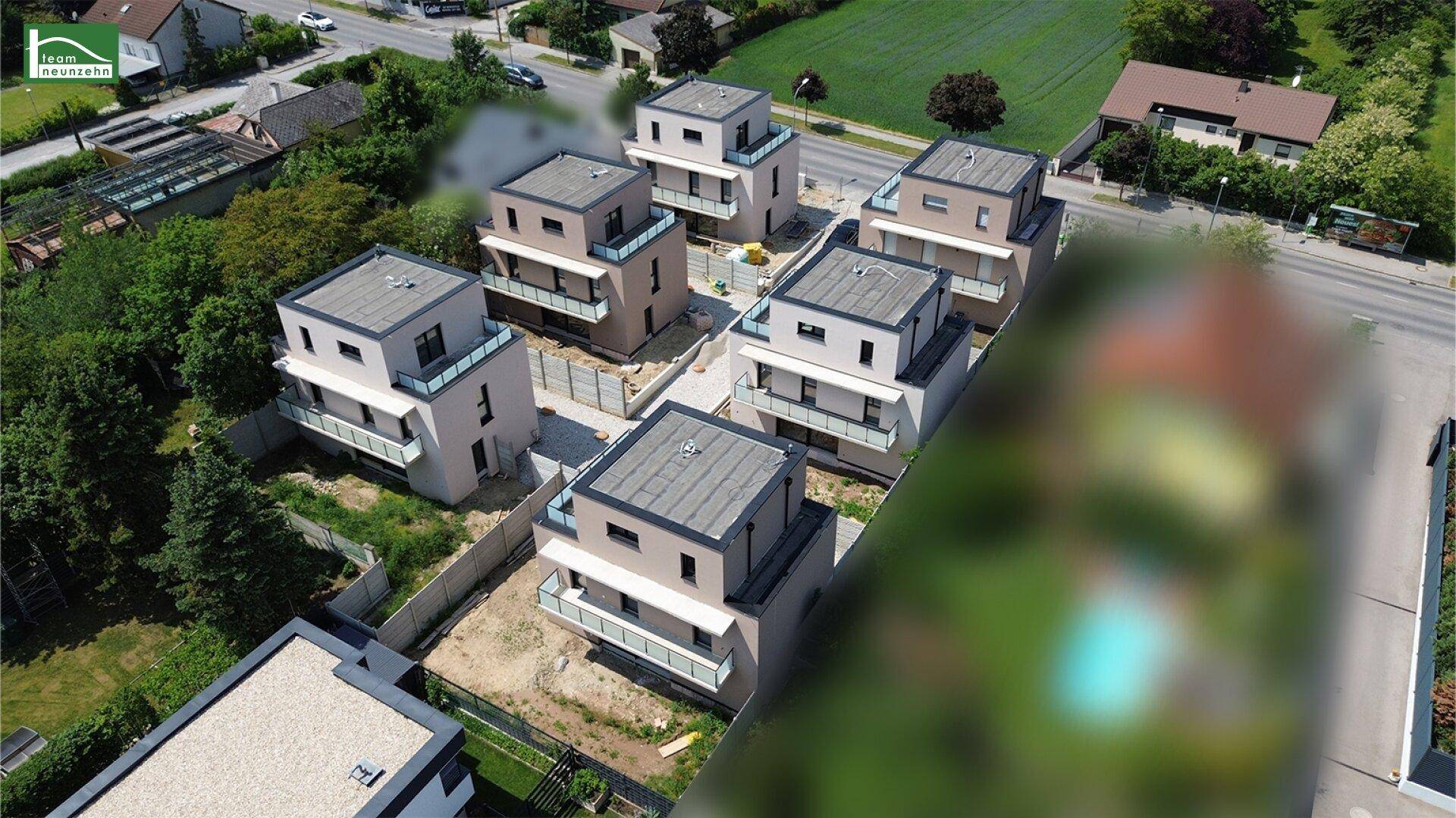 Ansicht einer modernen Wohnanlage mit mehreren Neubauten und ihren individuellen Außenbereichen.