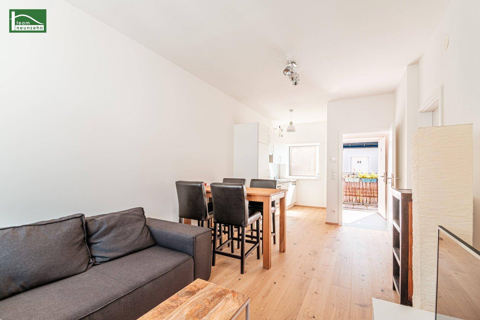 Heller offener Wohn- und Essbereich mit Holzboden und Zugang zu einem kleinen Balkon.