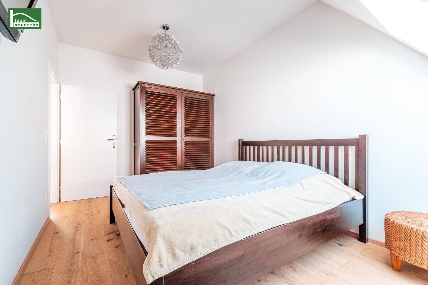 Helles Schlafzimmer mit Holzboden, großem Kleiderschrank und Dachschräge, die den Raum gemütlich macht.