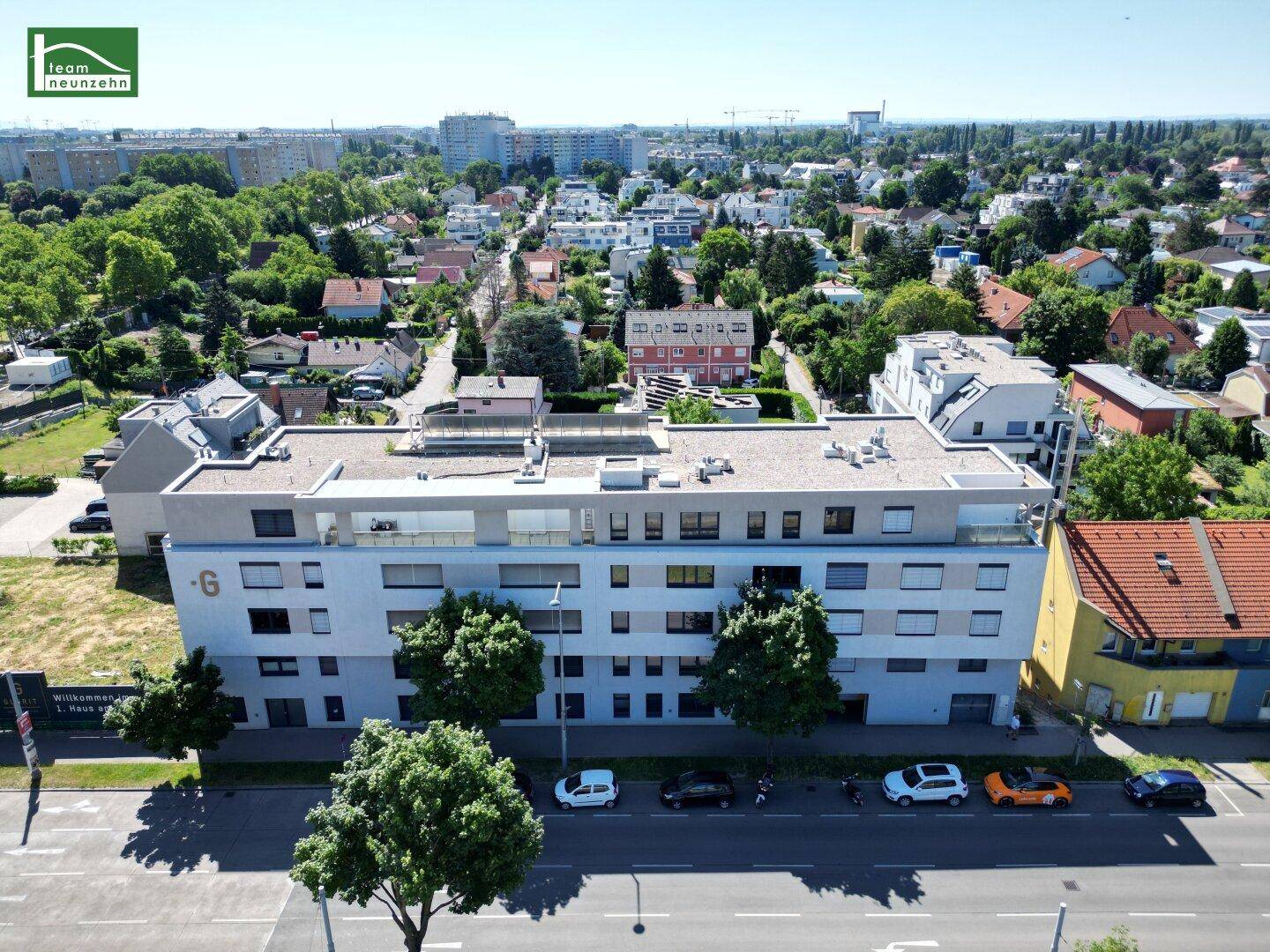 Moderne Wohnanlage mit Flachdach und grüner Umgebung aus der Vogelperspektive.