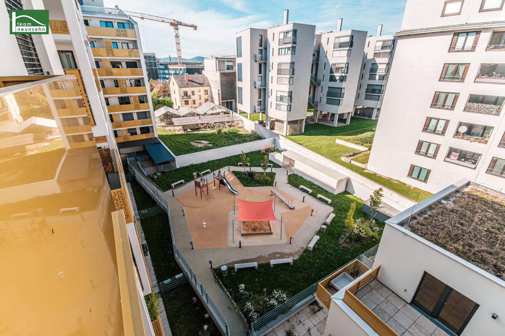 Grüner Innenhof mit modernem Kinderspielplatz und umliegenden Wohngebäuden.