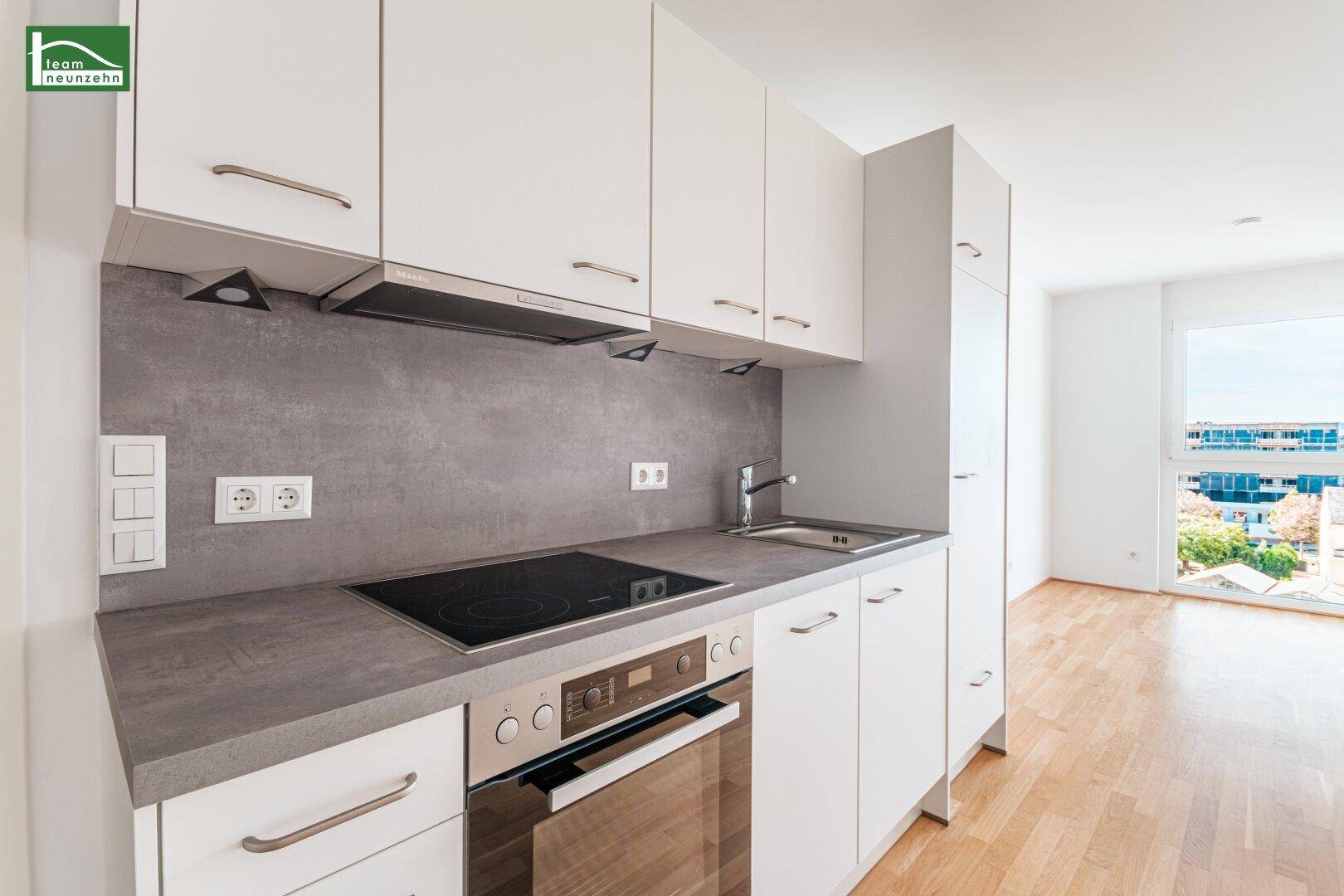 Moderne Küchenzeile mit weißen Schränken, integriertem Backofen und Induktionskochfeld.