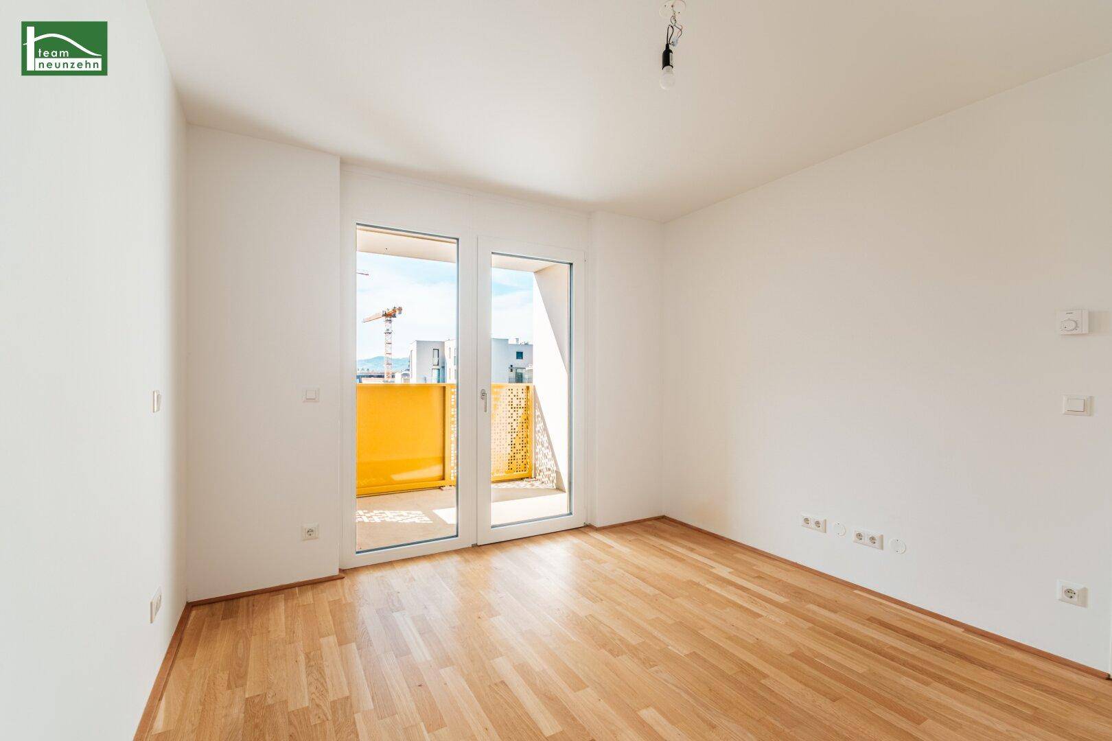 Helles Zimmer mit Parkettboden und direktem Zugang zu einem sonnigen Balkon.